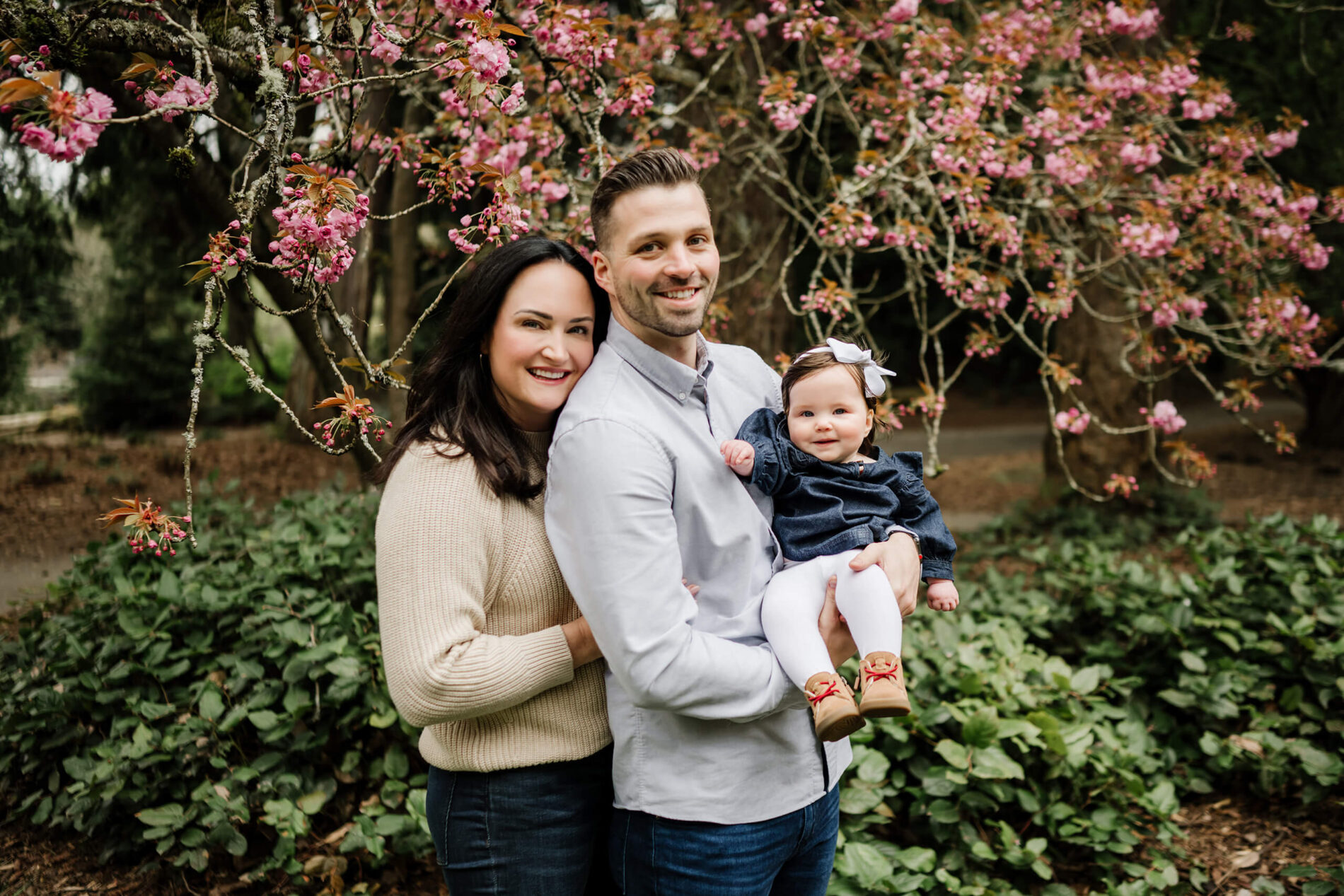 Family portrait with blooming pink flowers in the background taken at WA Park Arboretum