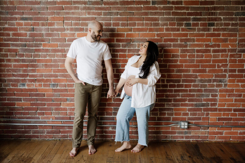 Indoor maternity portrait of a couple in front of an exposed brick wall taken in Seattle studio