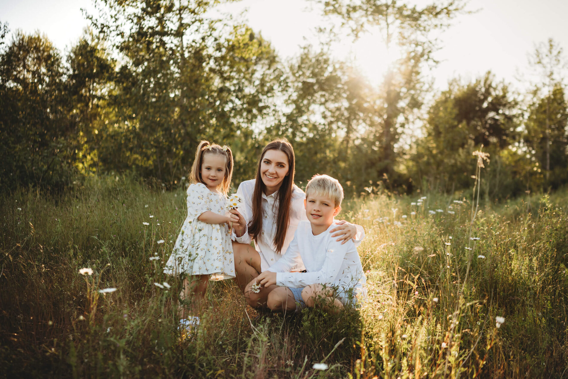 Portrait of mom with son and daughter smiling during family photoshoot in wildflower field