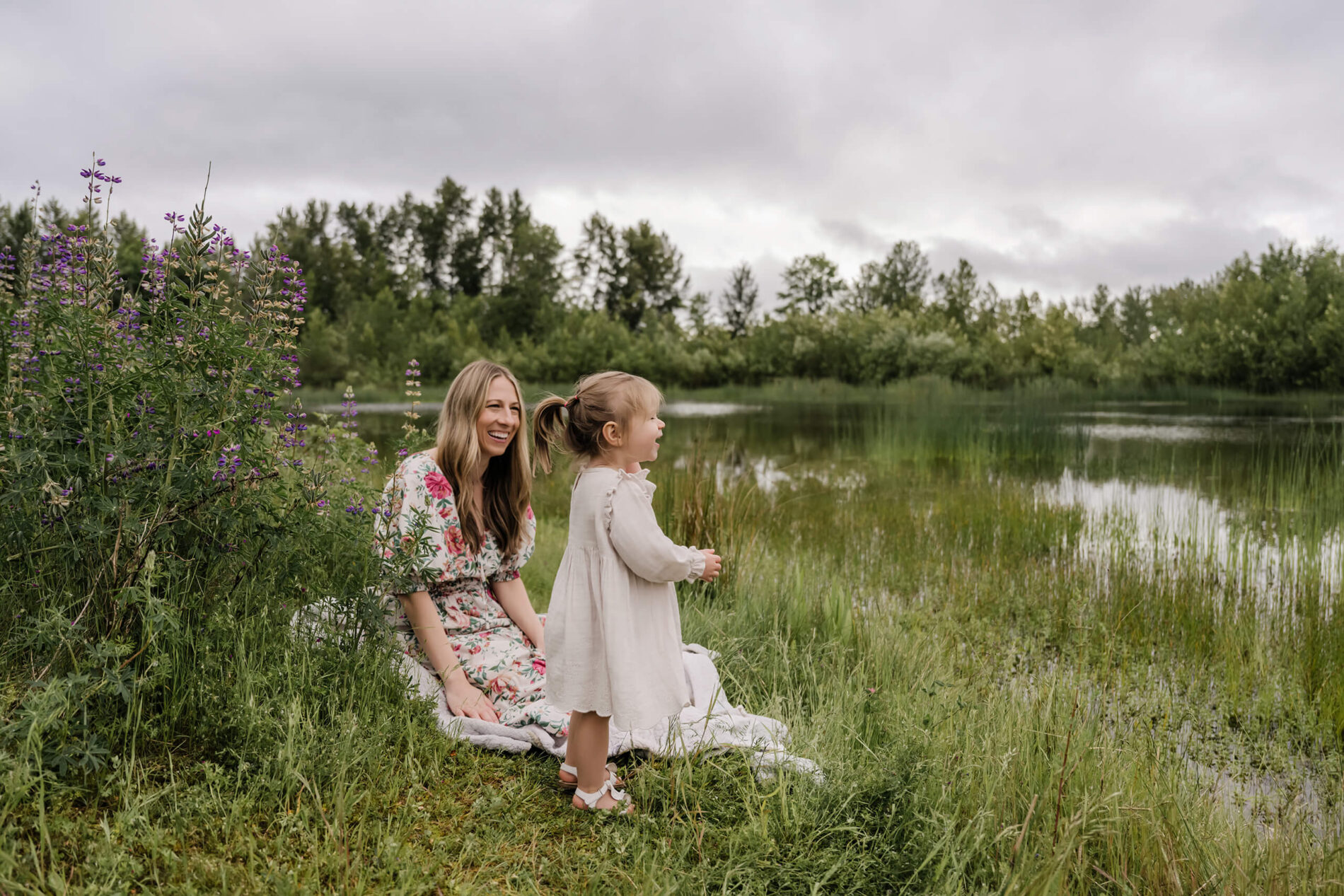 Mom playing with daughter during family photoshoot in lupine field in Seattle