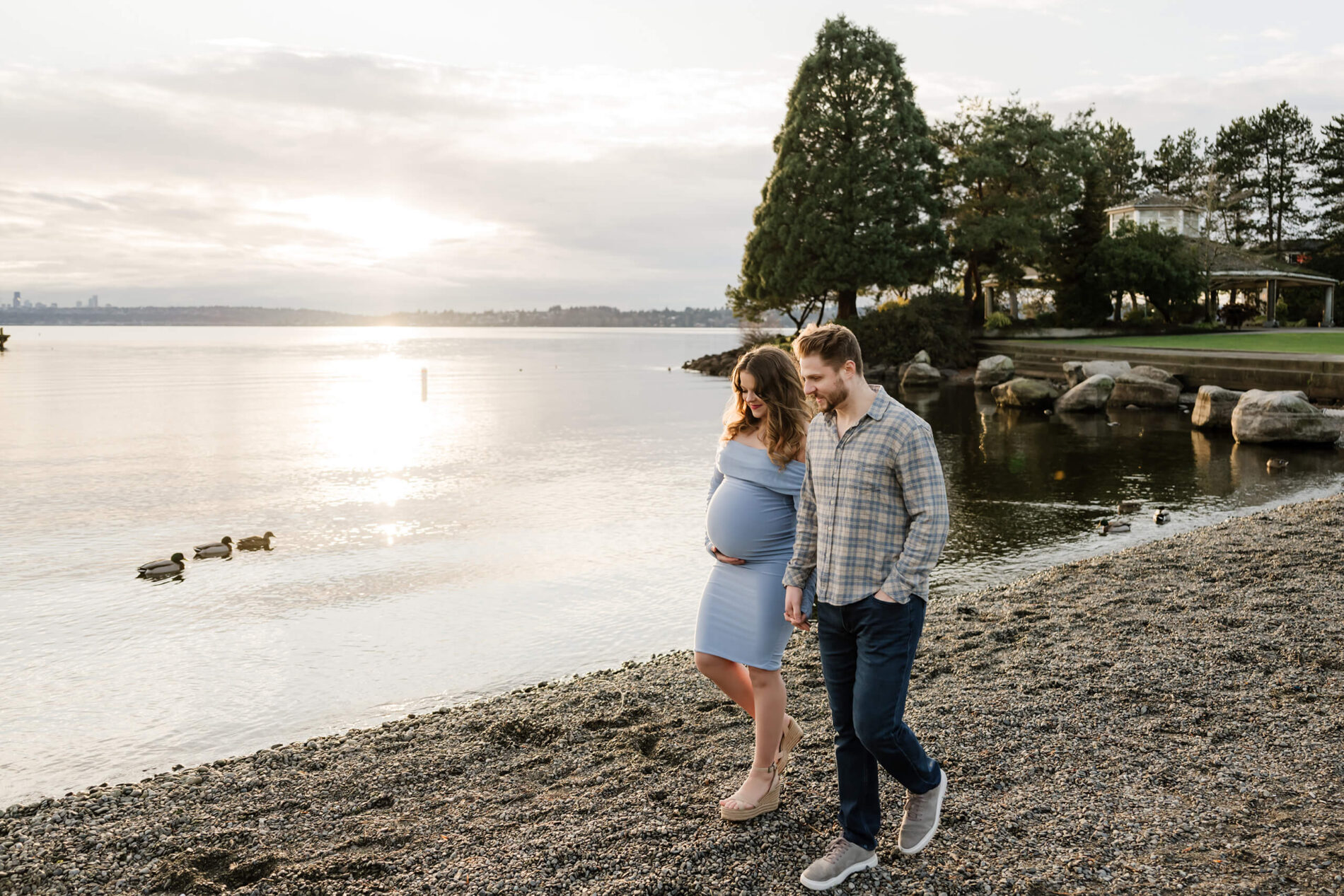 Kirkland maternity photographer posing a couple on Kirkland Marina Park Beach with Lake Washington in the background