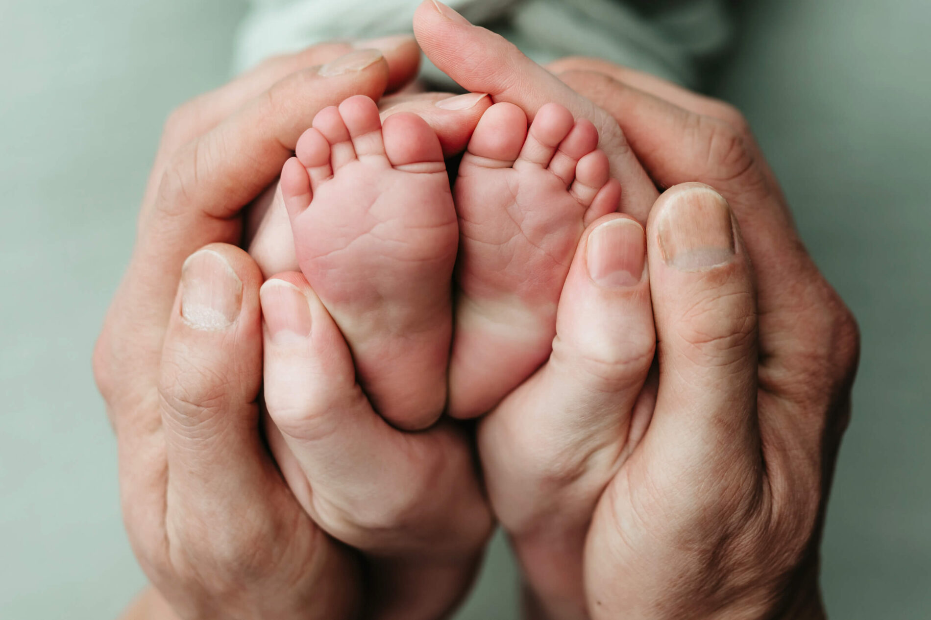 Newborn footsie curl: parents’ thumbs meet as they cup their baby’s soft pink heels.
