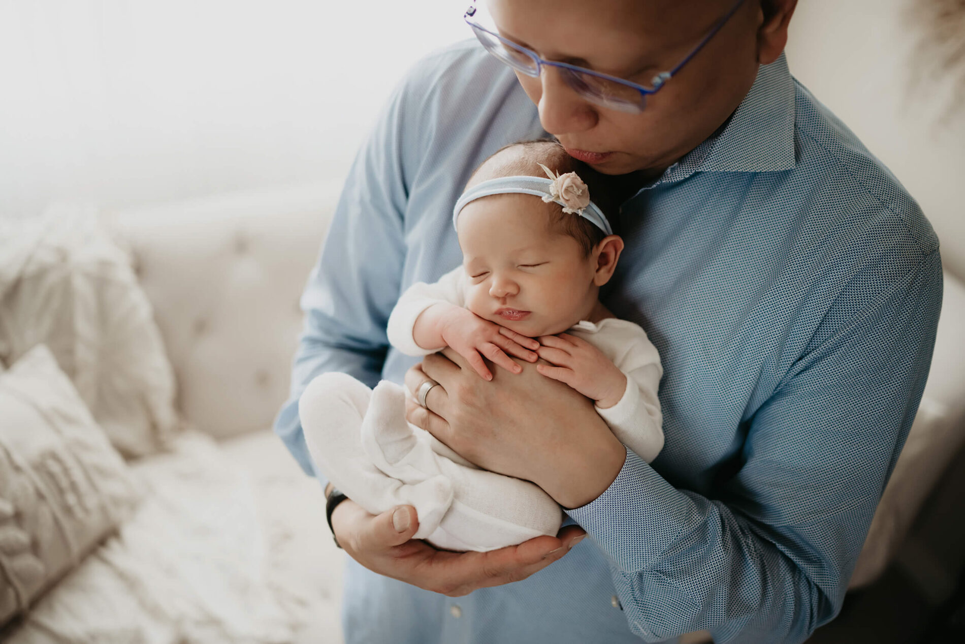 Father’s proud look as he holds his daughter, backlight creating a soft effect.