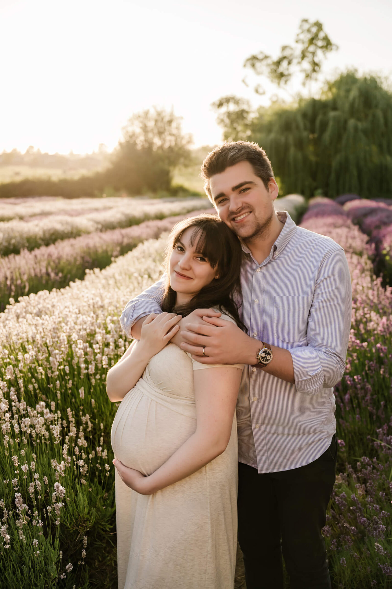 Young couple hugging during maternity session in a lavender field