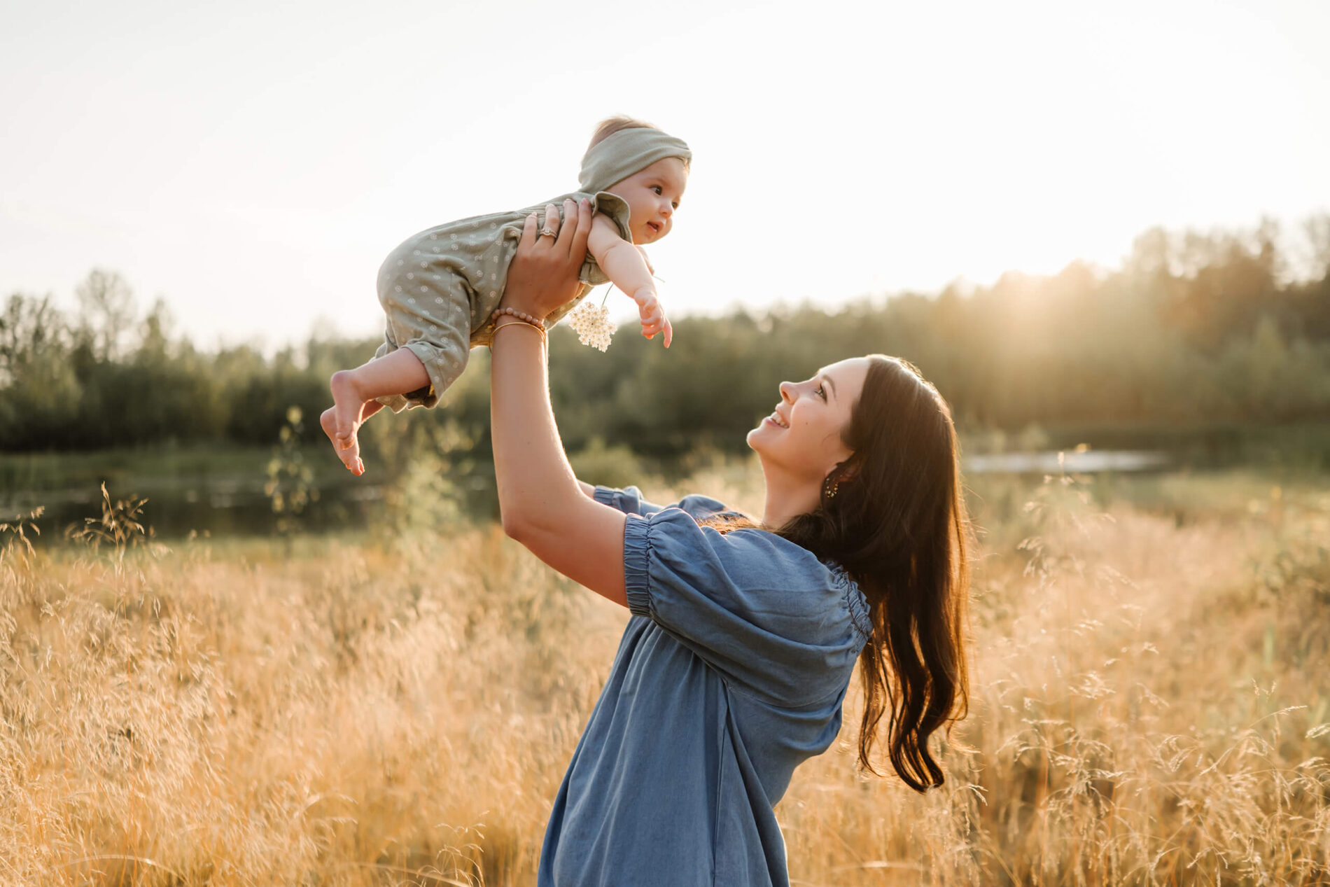 Mother lifting baby toward the sunset in a golden meadow near Bellevue and Kirkland.