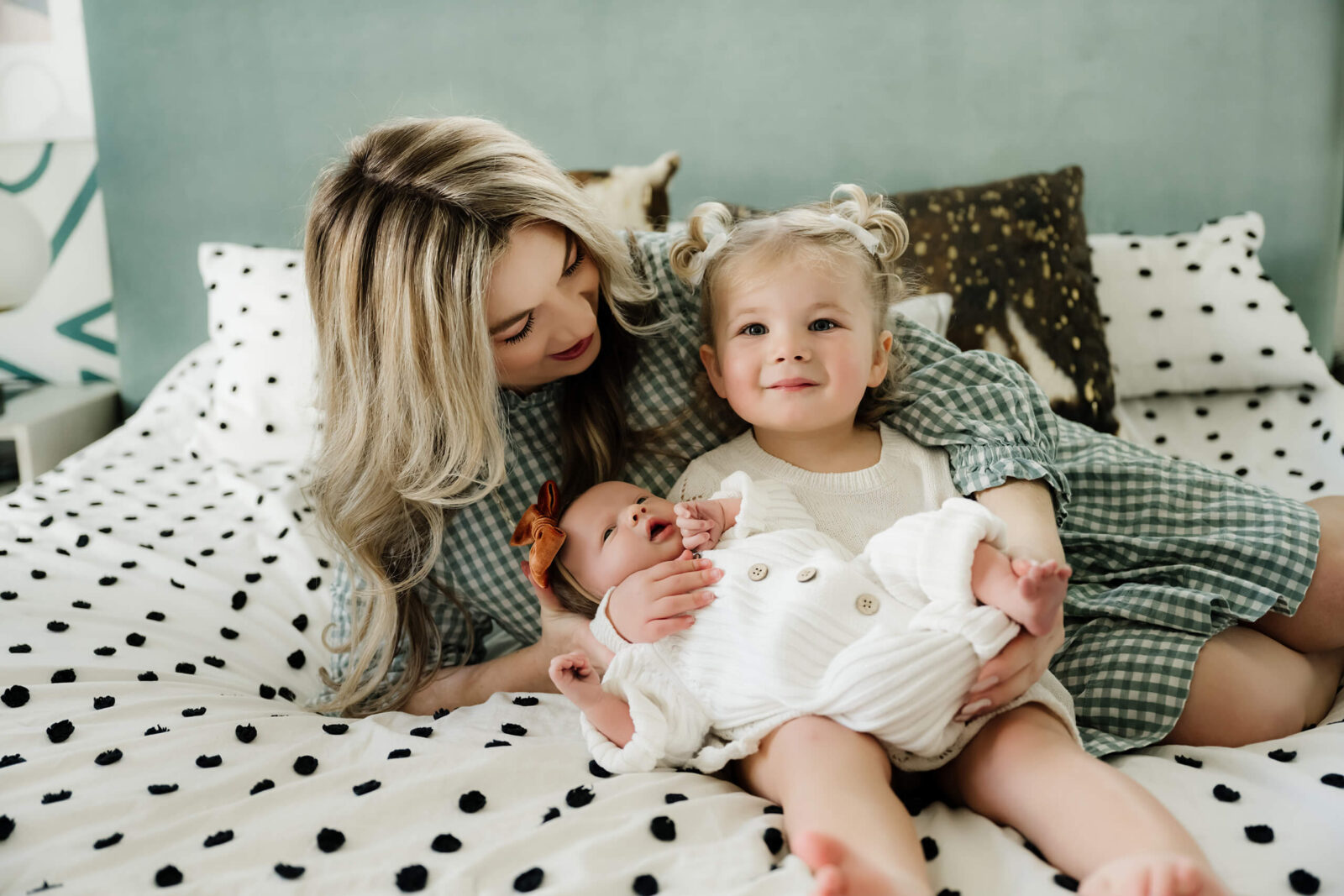Mother cuddling with her toddler and newborn baby on the bed during an in-home lifestyle newborn photography session in Seattle.