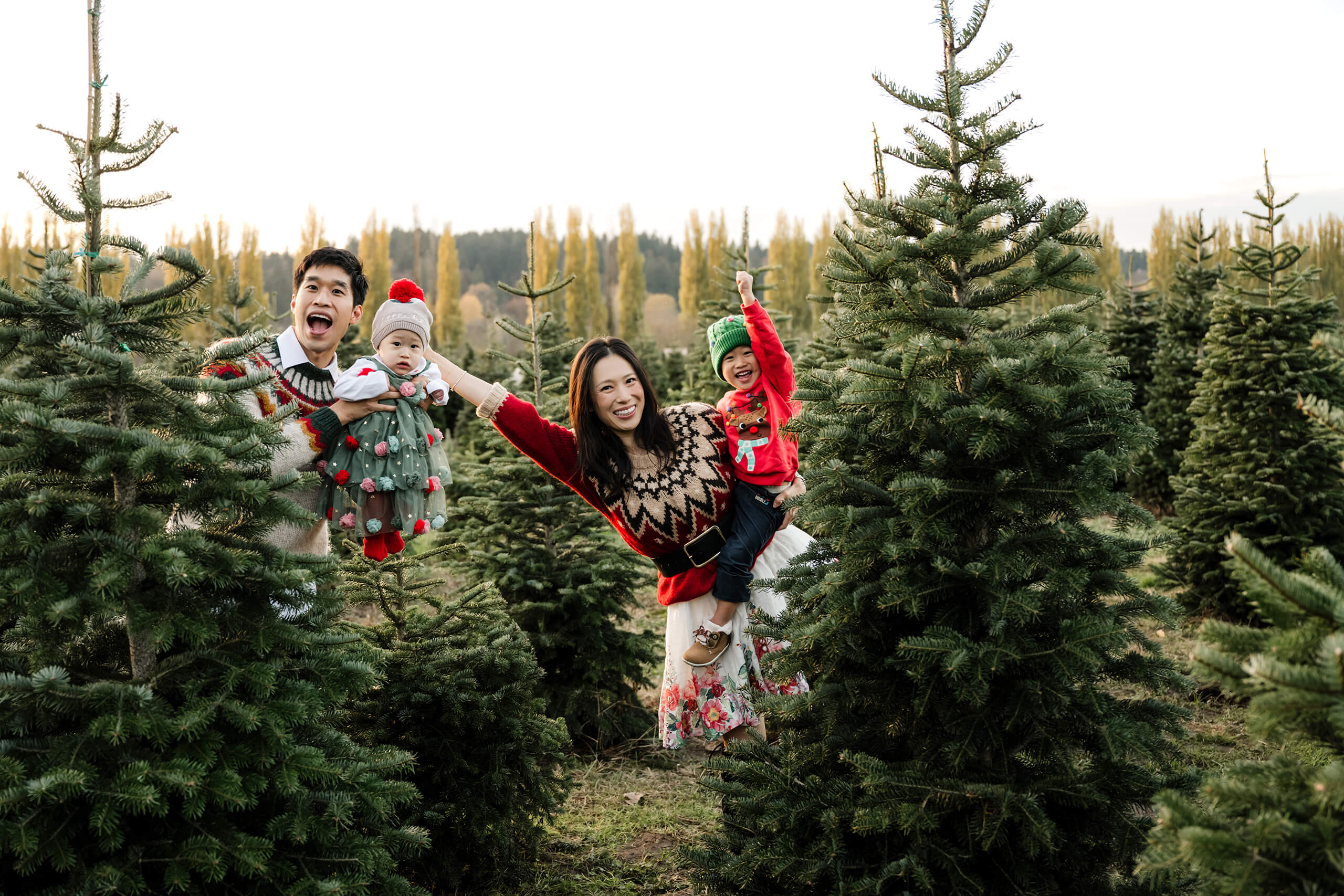 Family playing together – Festive holiday mini session at a Seattle Christmas tree farm with parents and kids in sweaters.