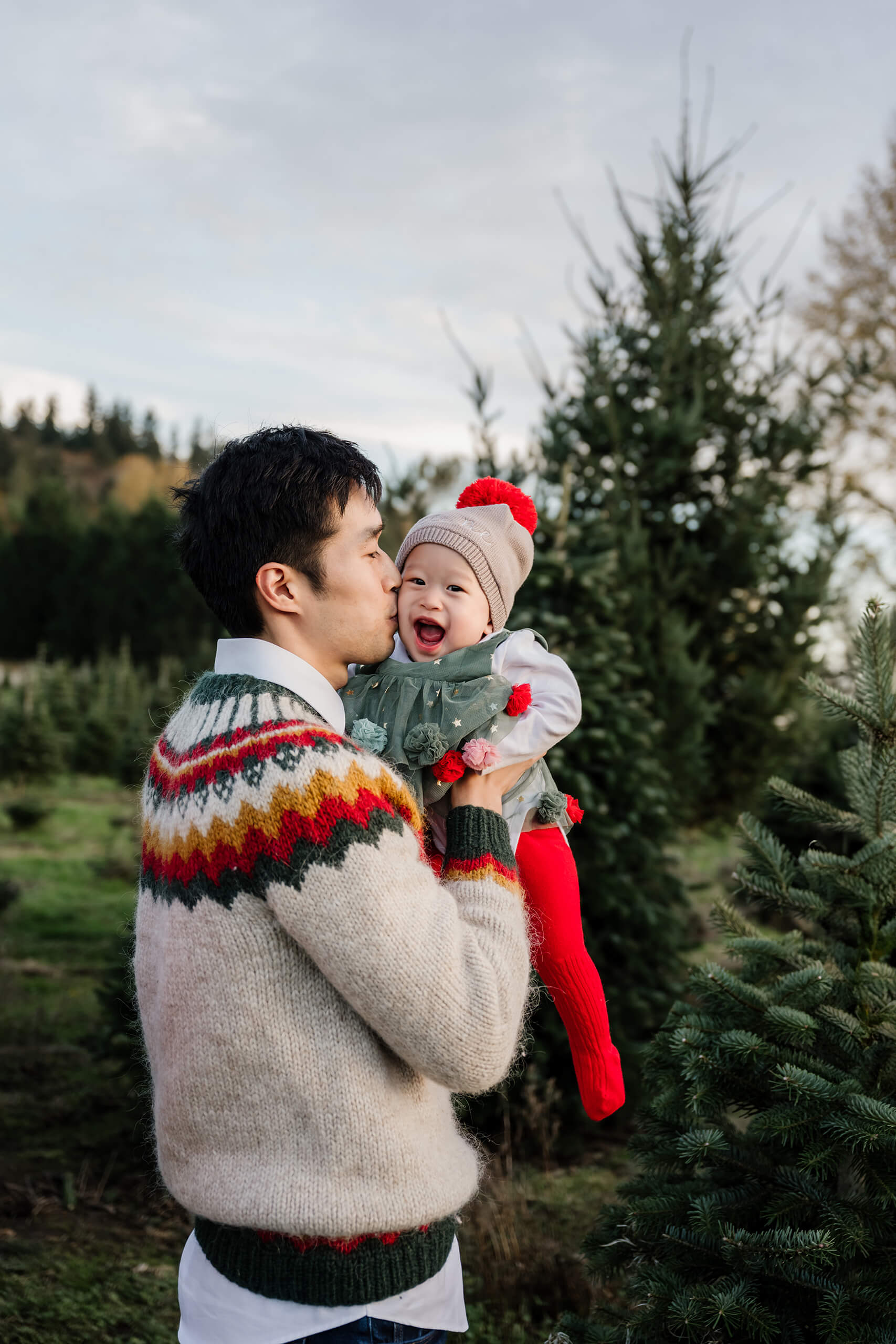 Father kissing baby – Sweet family moment during Seattle Christmas tree farm holiday mini session.