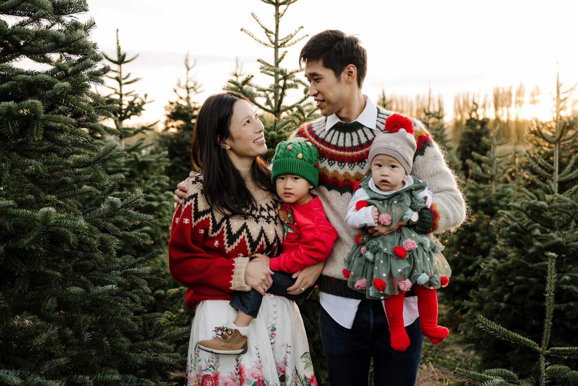 Family portrait at sunset – Seattle holiday mini session with family of four surrounded by Christmas trees.