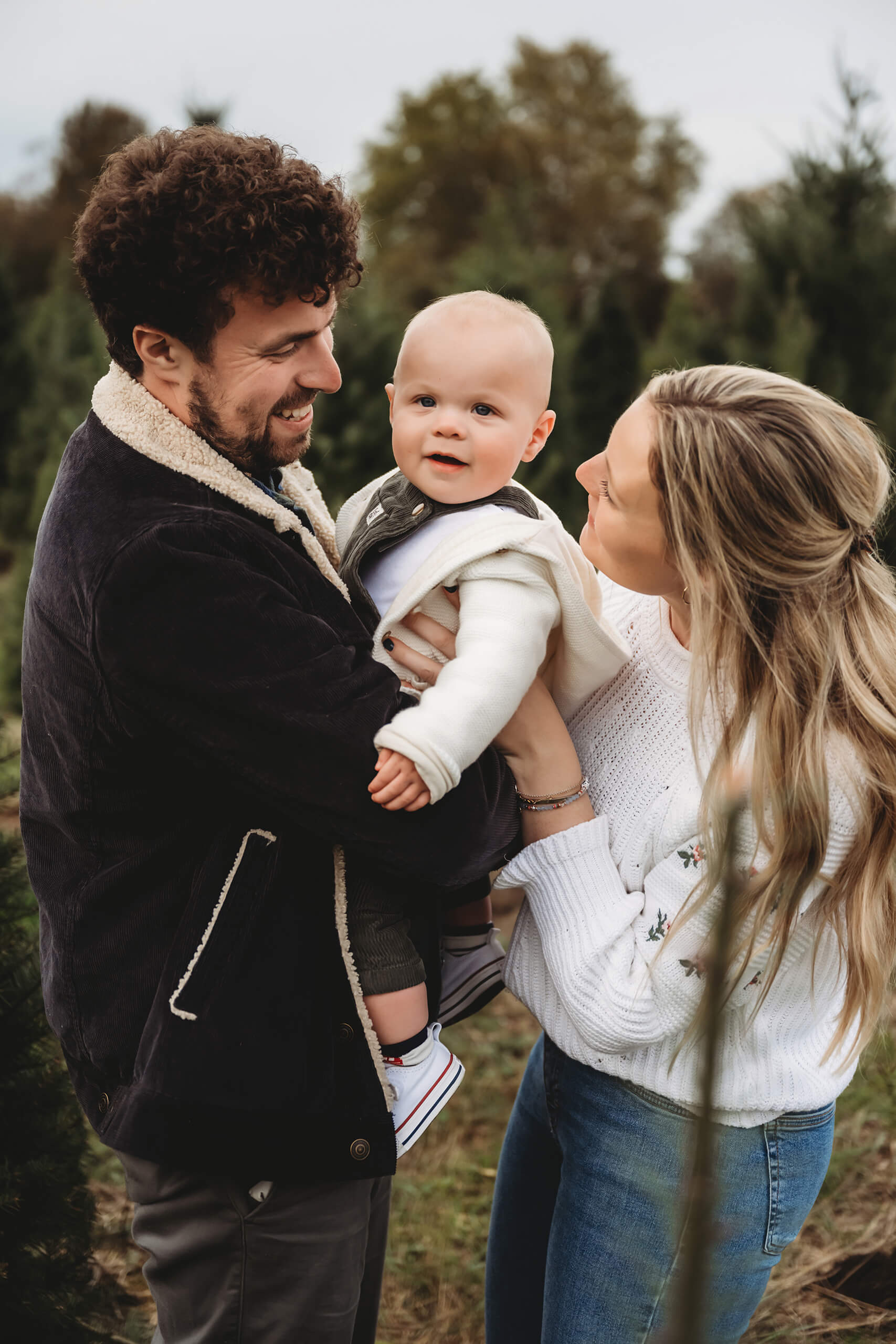 Parents holding baby – Cozy Seattle holiday mini session at tree farm with young child.