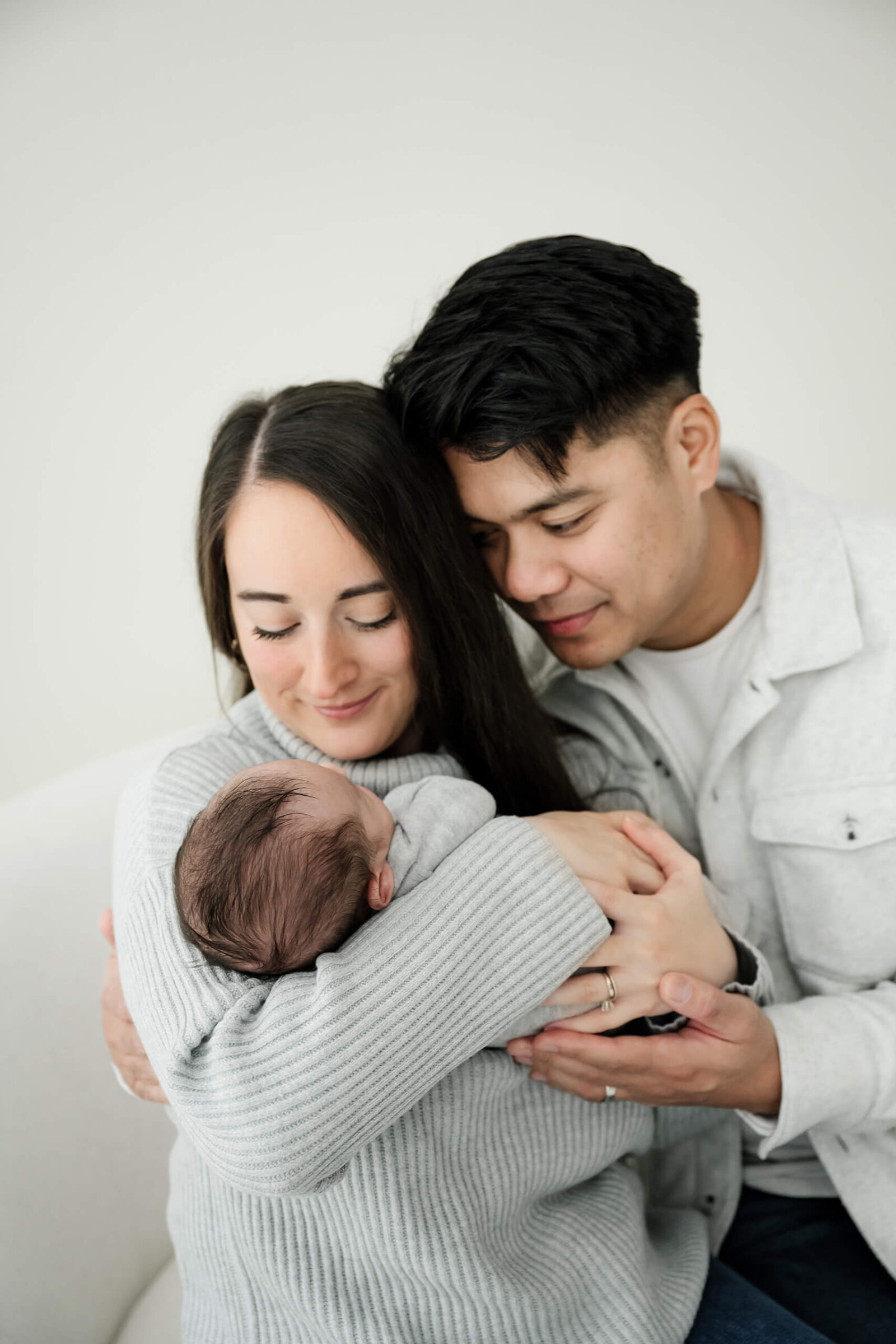 Parents embracing their baby together during an intimate, connection-centered newborn photo session.