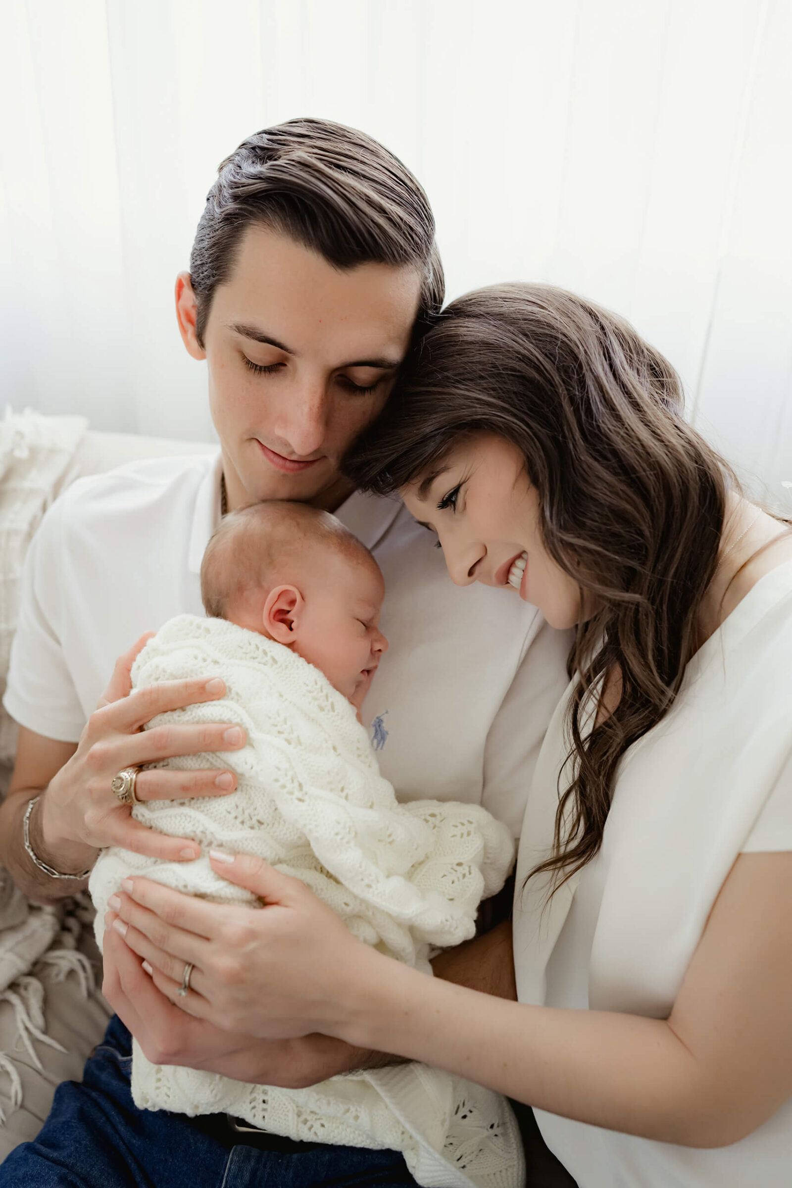 Father and mother holding their newborn baby together during a cozy, love-filled newborn photo session in Seattle.