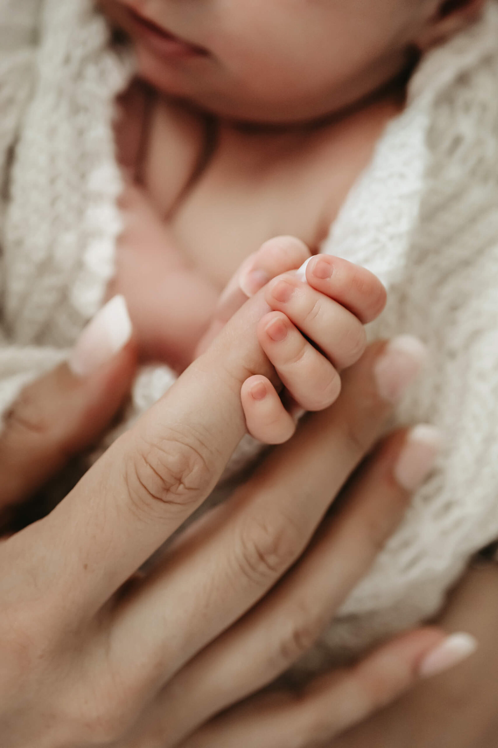 Close-up of newborn’s tiny hand holding parent’s finger during a detail-focused, heartfelt newborn photo session.