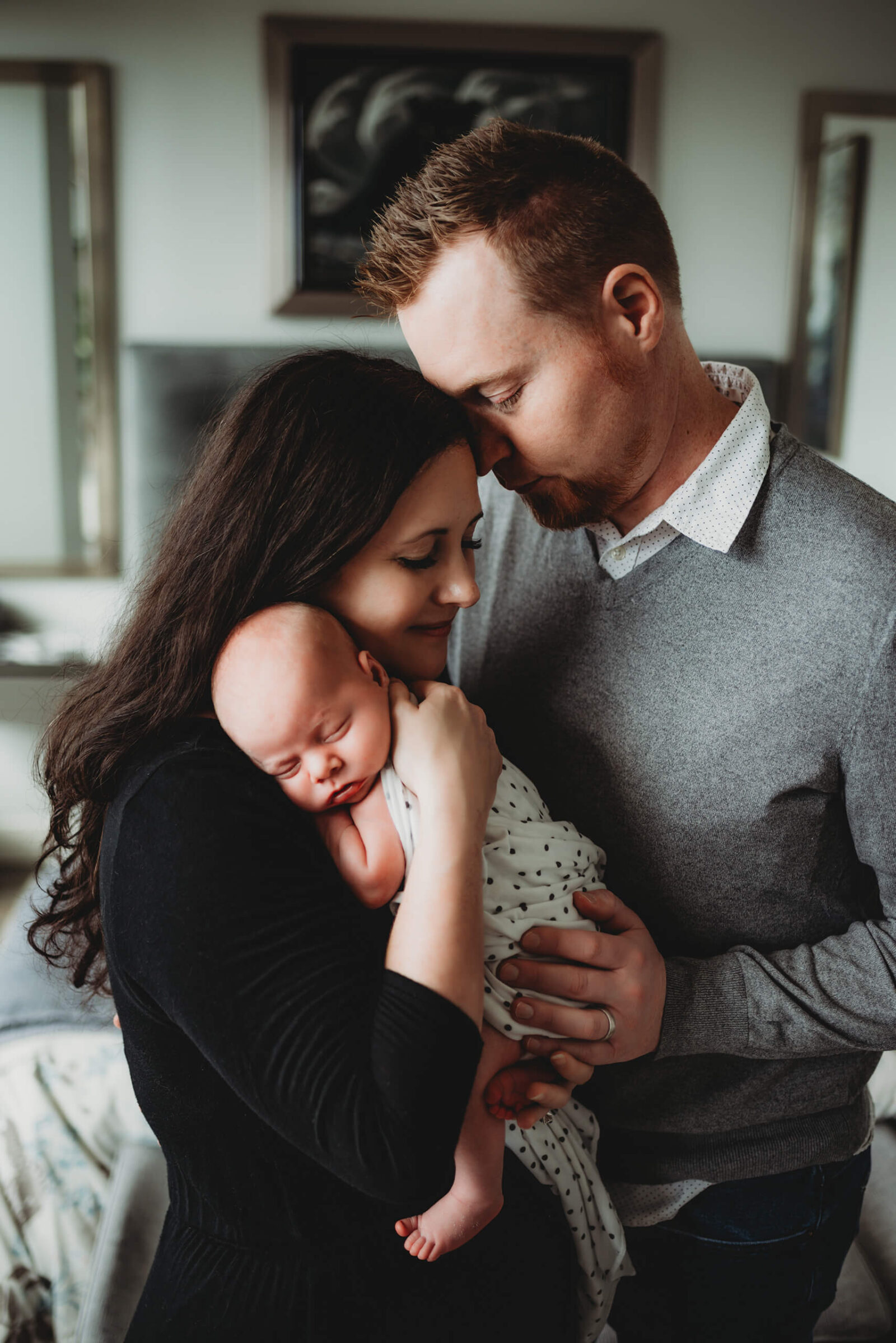 Parents embracing their newborn baby together during a warm, light-filled in-home lifestyle newborn session in Seattle.