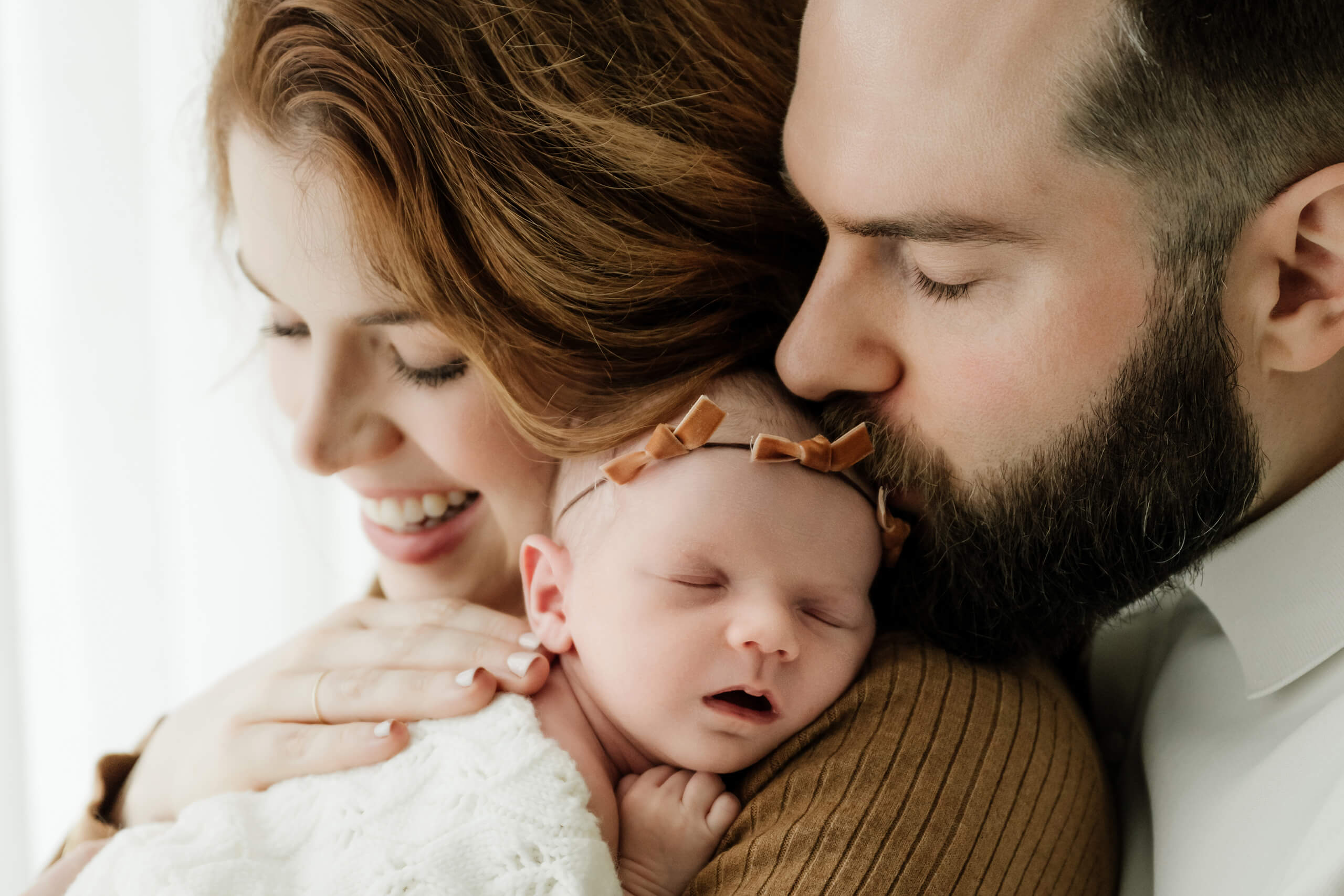 Mother and father holding their newborn baby during a light-filled Seattle newborn photoshoot by Lana Sky Photography.