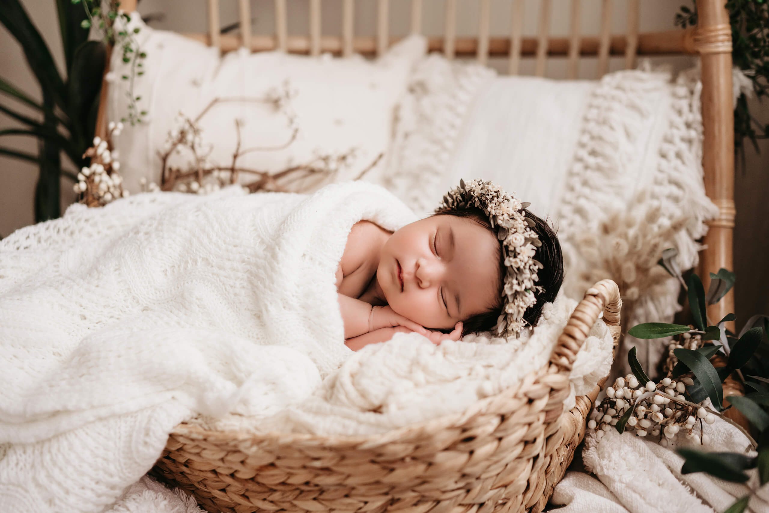 Sleeping newborn in a woven basket with floral crown during a cozy, natural newborn photoshoot in Seattle.