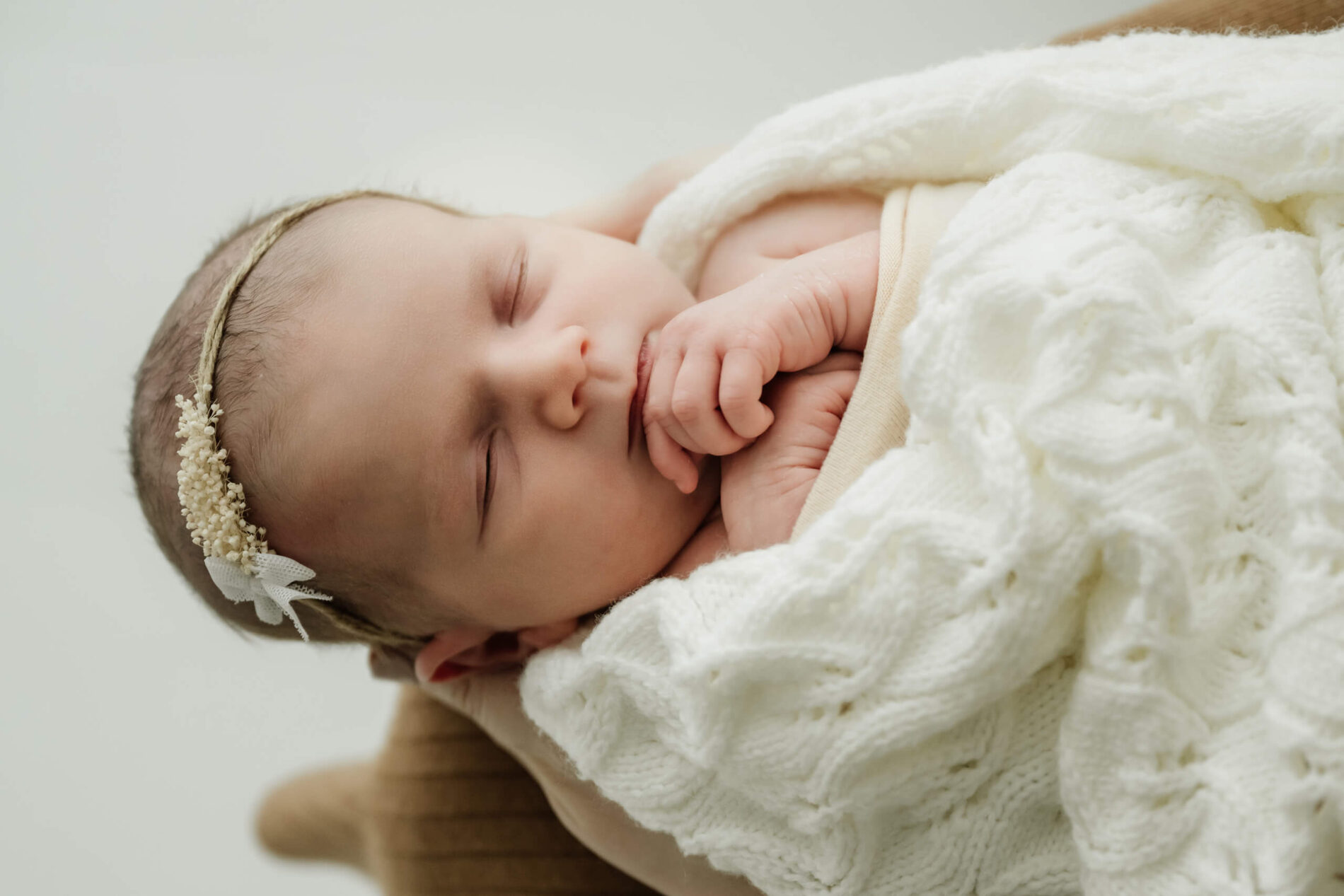 Newborn resting on a parent’s lap in a cozy knit wrap for Seattle family newborn photography