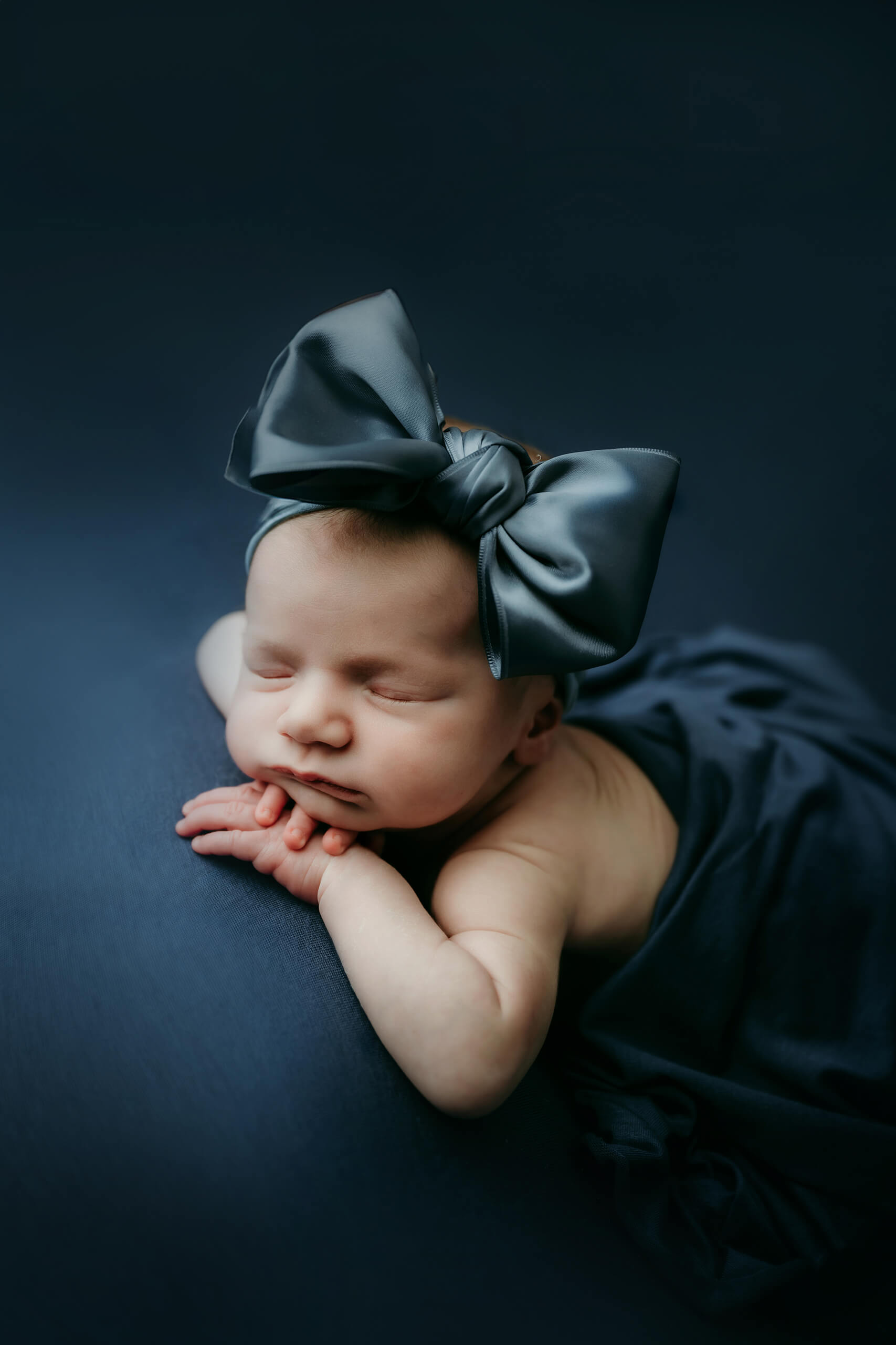 Close up of a newborn resting on her tummy with a bow headband for a Seattle newborn family photoshoot