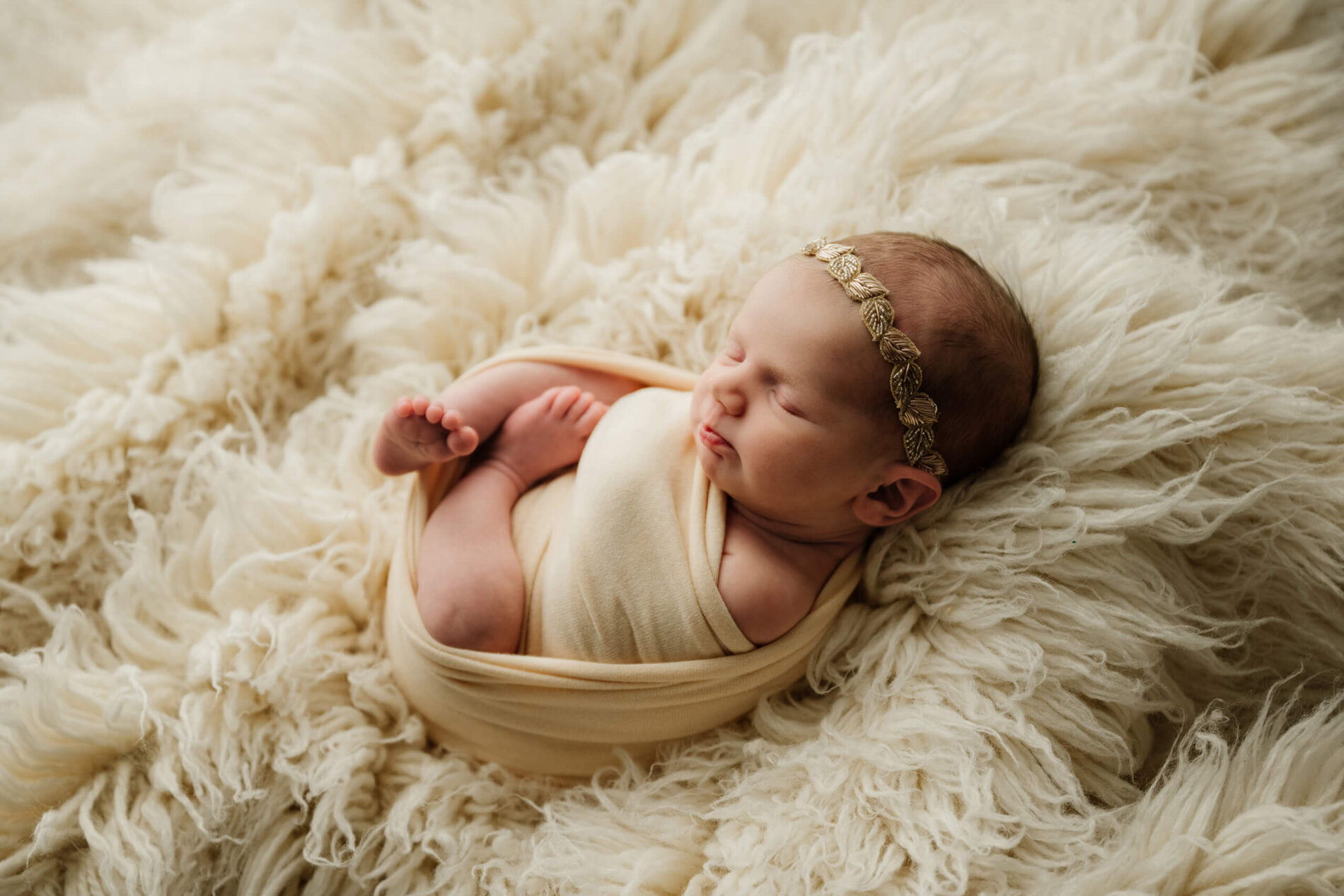 Swaddled newborn lying on a fluffy cream blanket during a Seattle family newborn photoshoot