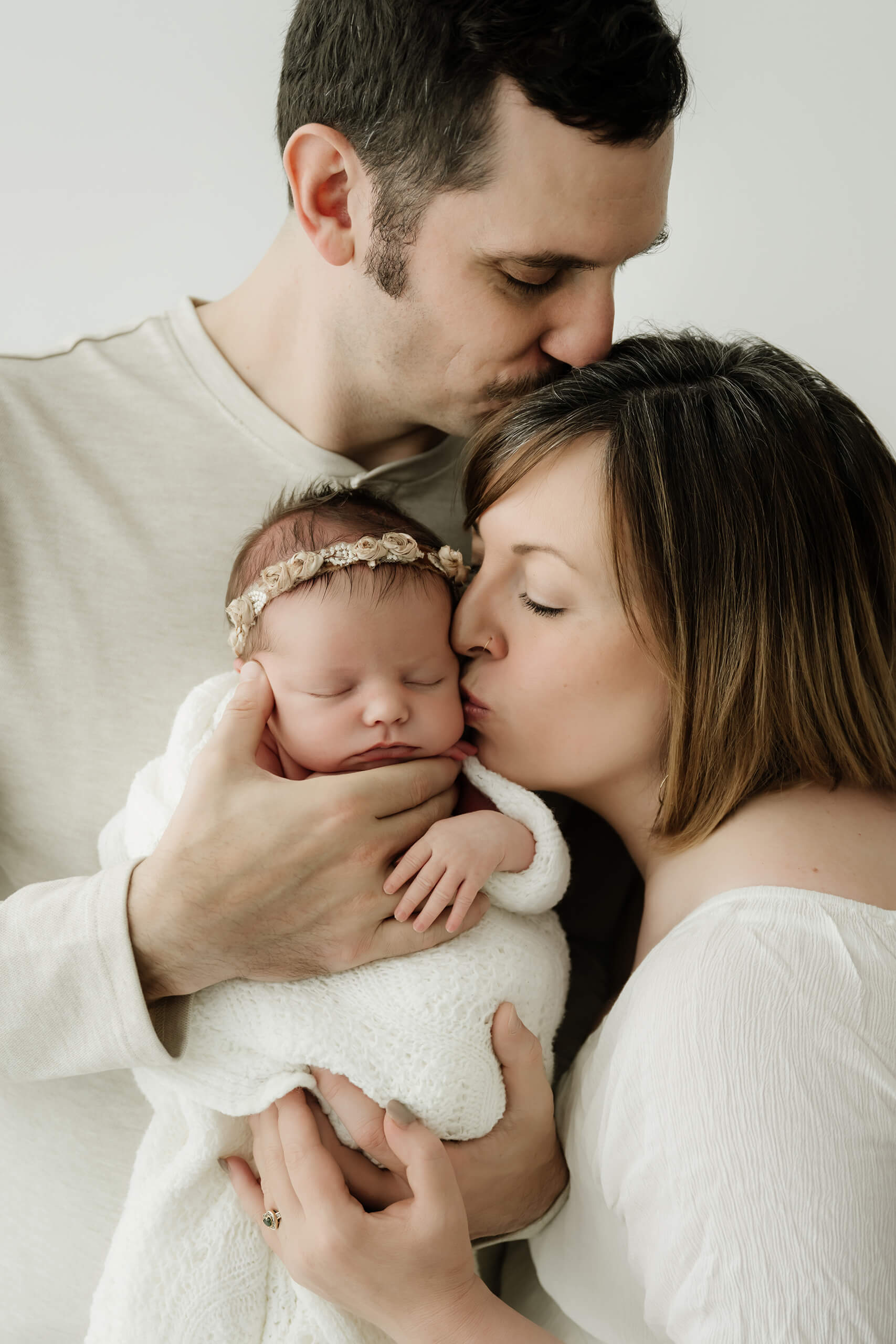 Close-up of parents holding their wrapped newborn together, highlighting quiet connection during a minimalist studio newborn session in Seattle.