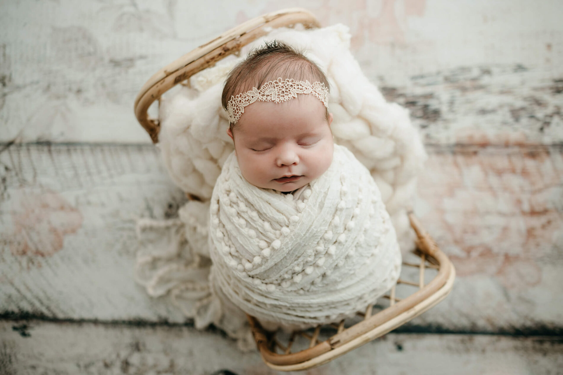 Close-up of a sleeping newborn baby wrapped in white, natural textures and soft light, Seattle newborn photography.