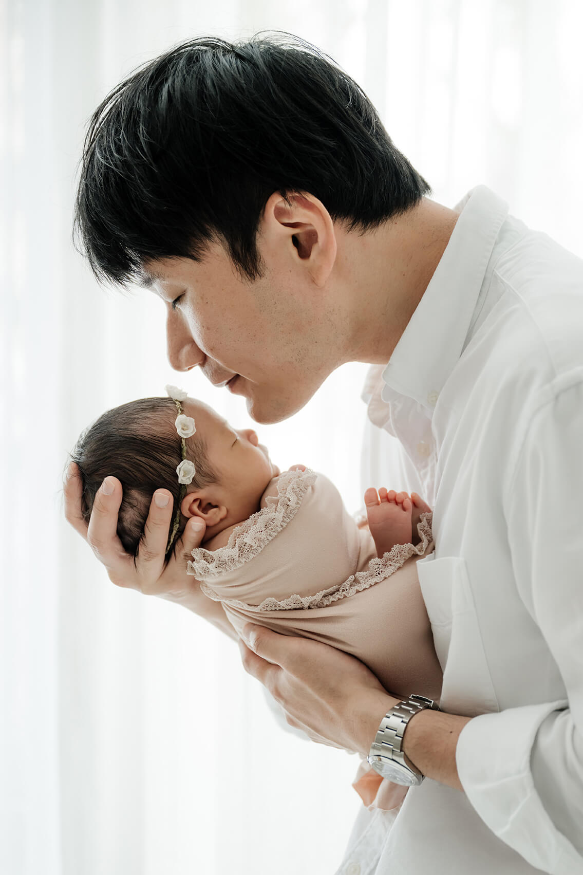 Father holding his newborn close and leaning in for a quiet moment, photographed during a simple, baby-focused newborn session in Seattle.