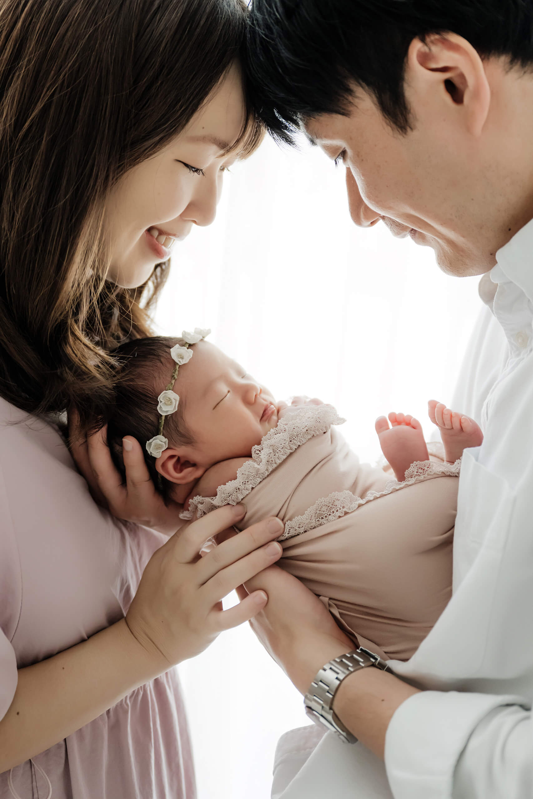 Mother and father holding their newborn close during a studio family photo, baby peacefully sleeping in a soft wrap, Seattle newborn photographer.