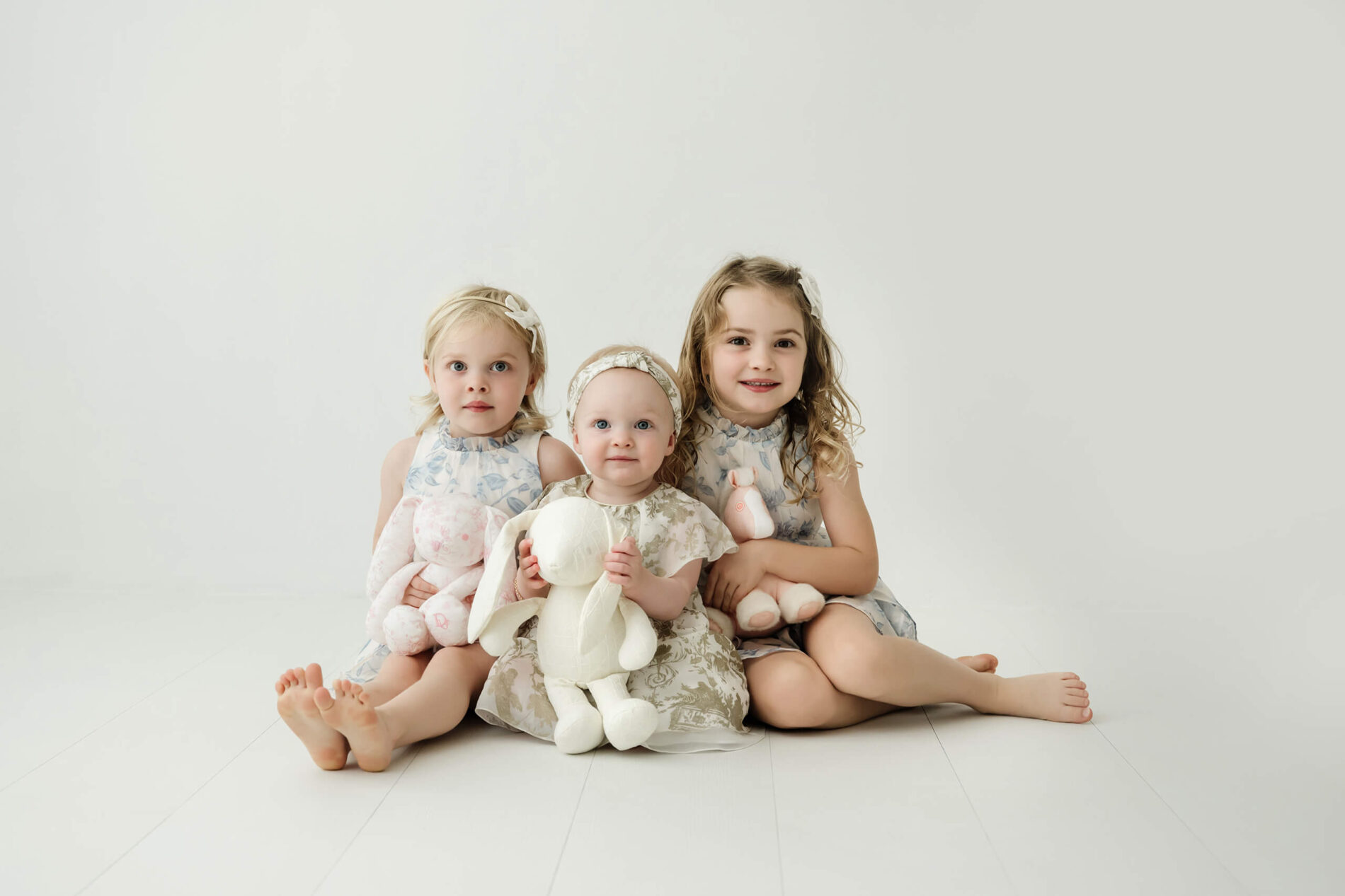 Sisters sitting close together with soft toys during a Seattle family studio session.
