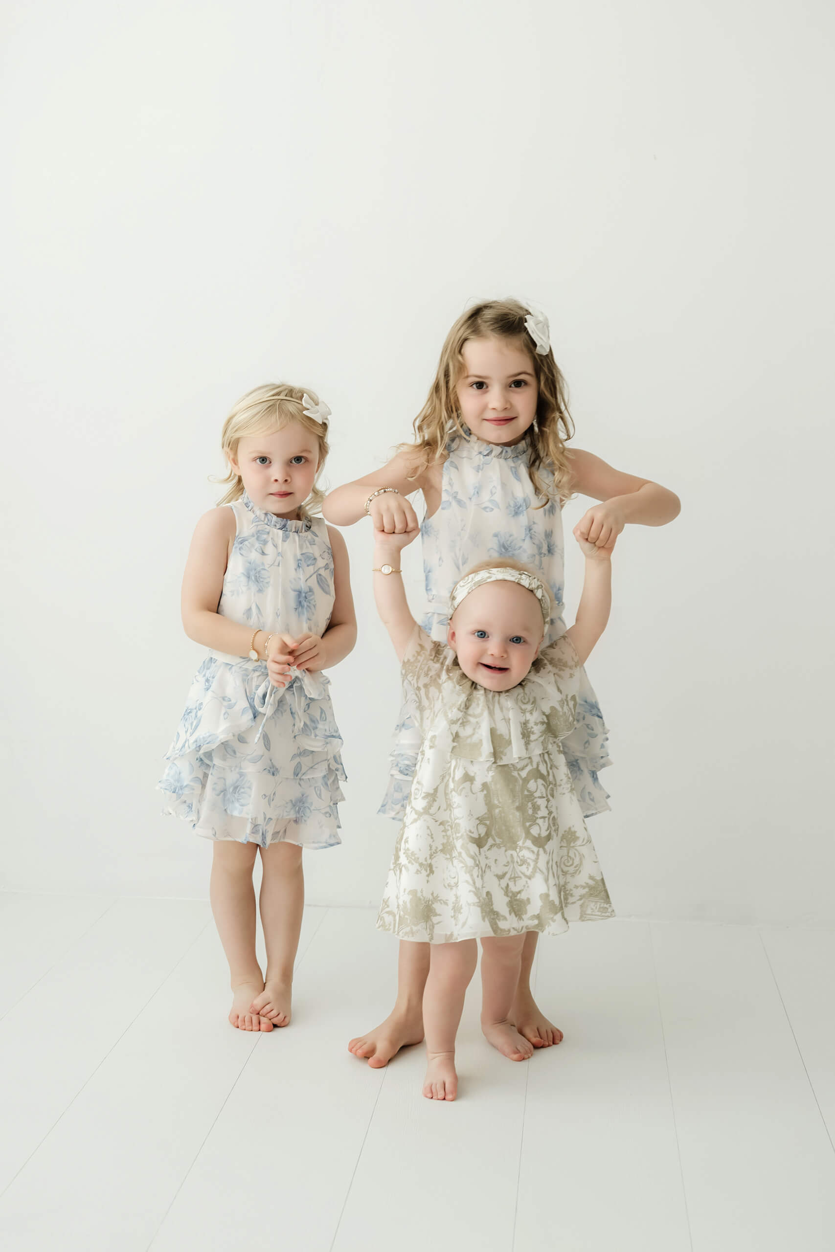 Three young siblings standing together in a bright family photography studio in Kirkland.