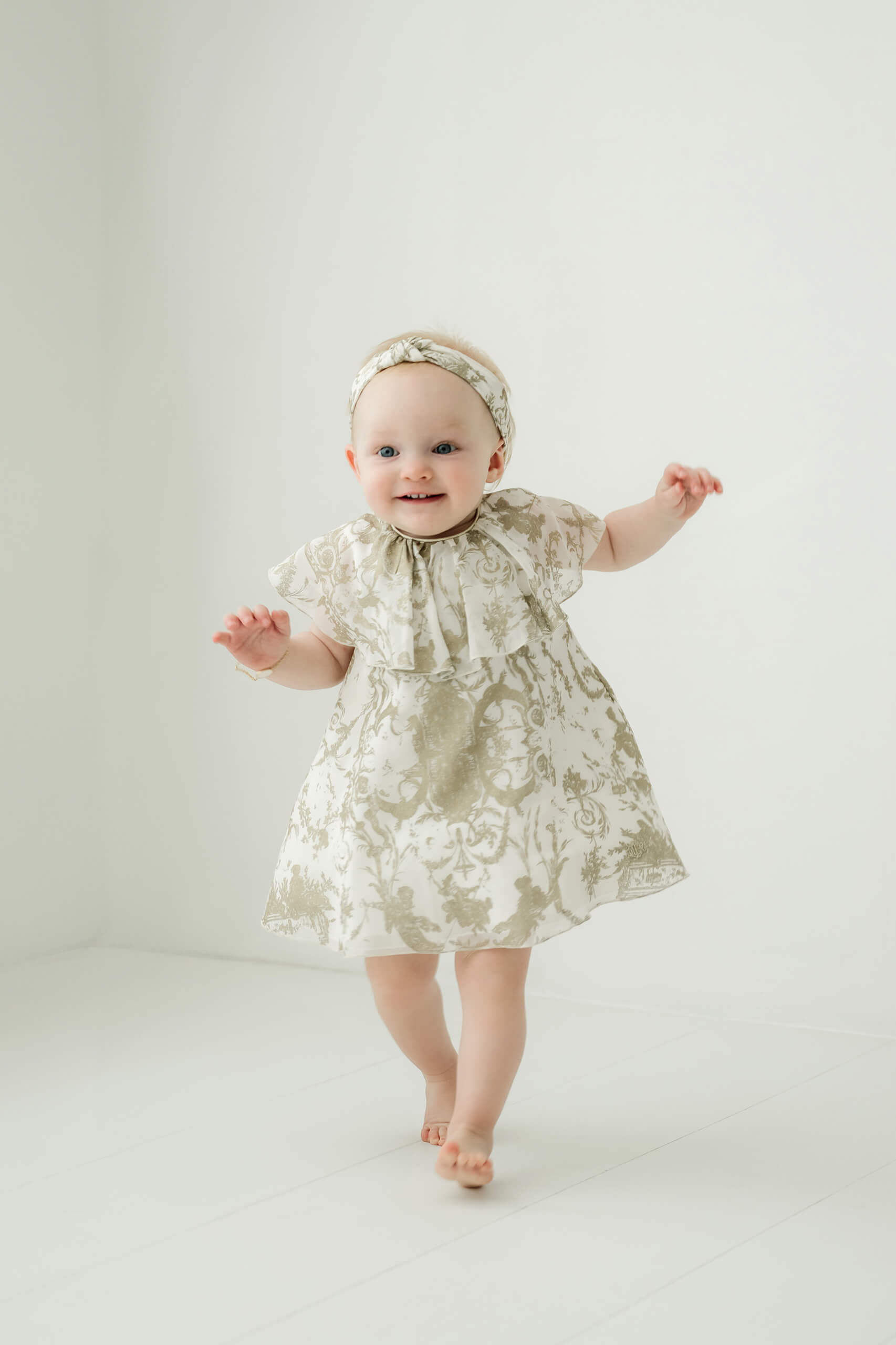 A baby standing independently in a minimal family studio photographed near Bellevue.