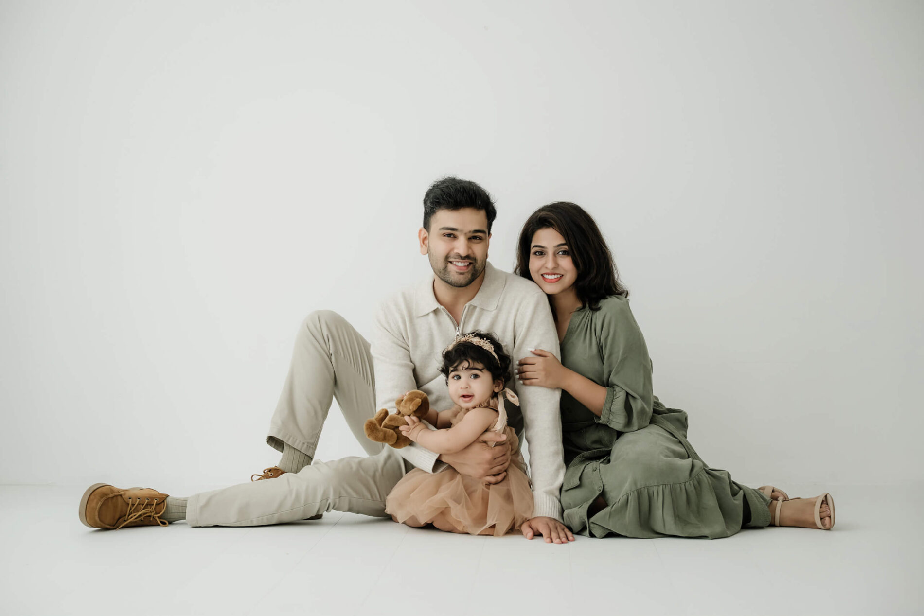 Parents sitting on the studio floor with their baby for a relaxed family photography session near Seattle.