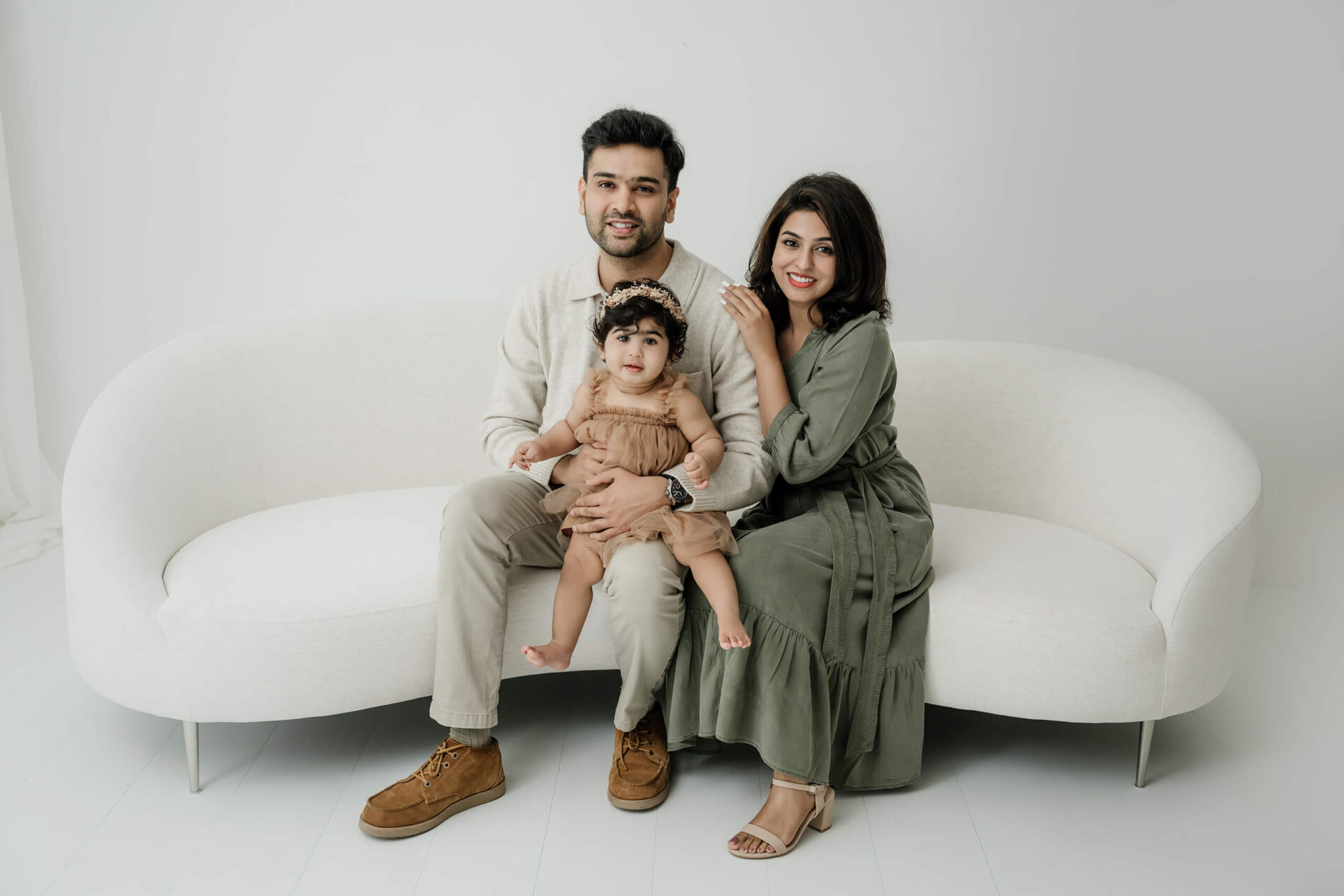 A young family seated together on a white studio couch during a Kirkland family photography session.