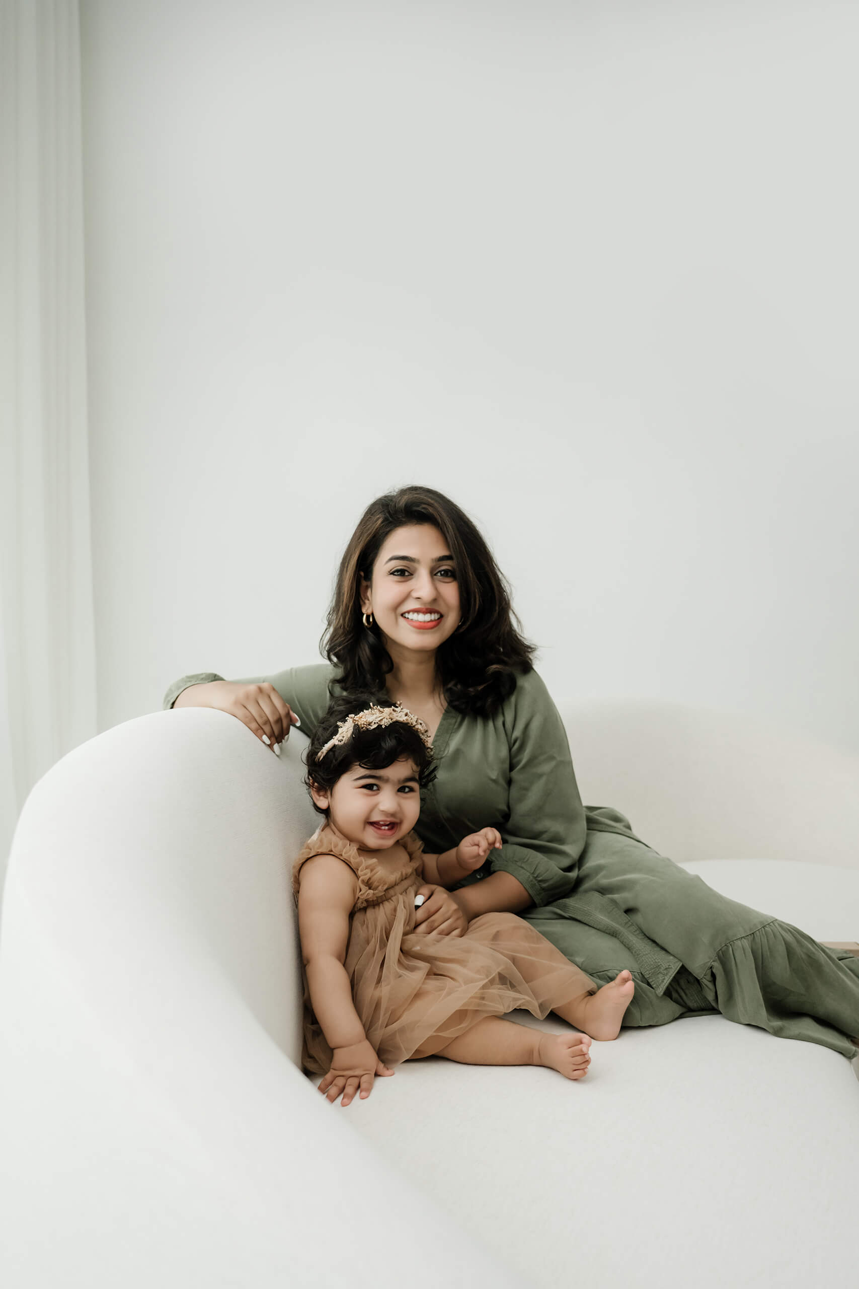 A mother and toddler sitting together on a neutral sofa during a Seattle family studio photography session.