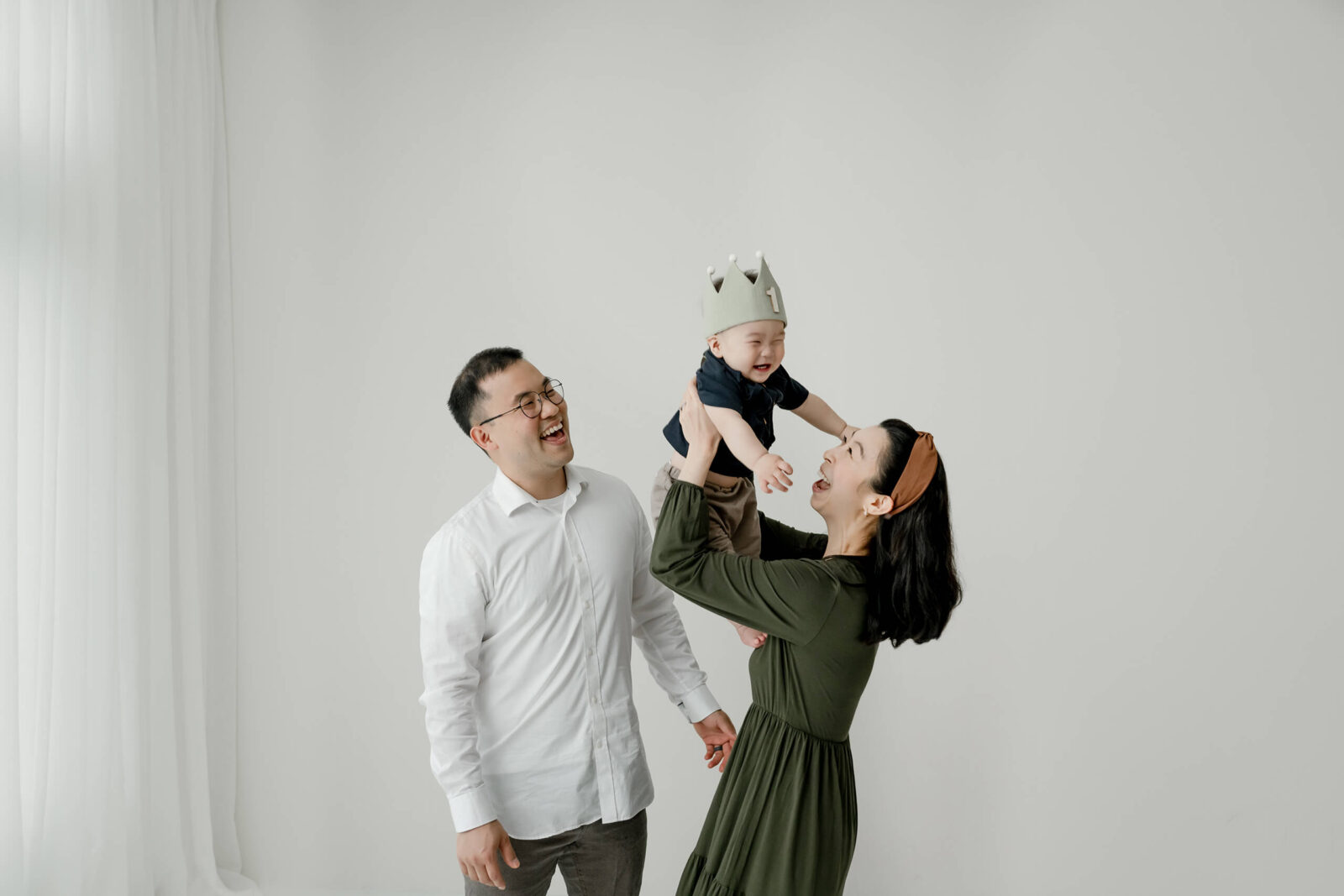 Parents lifting their baby into the air during a joyful family photography session in Kirkland.