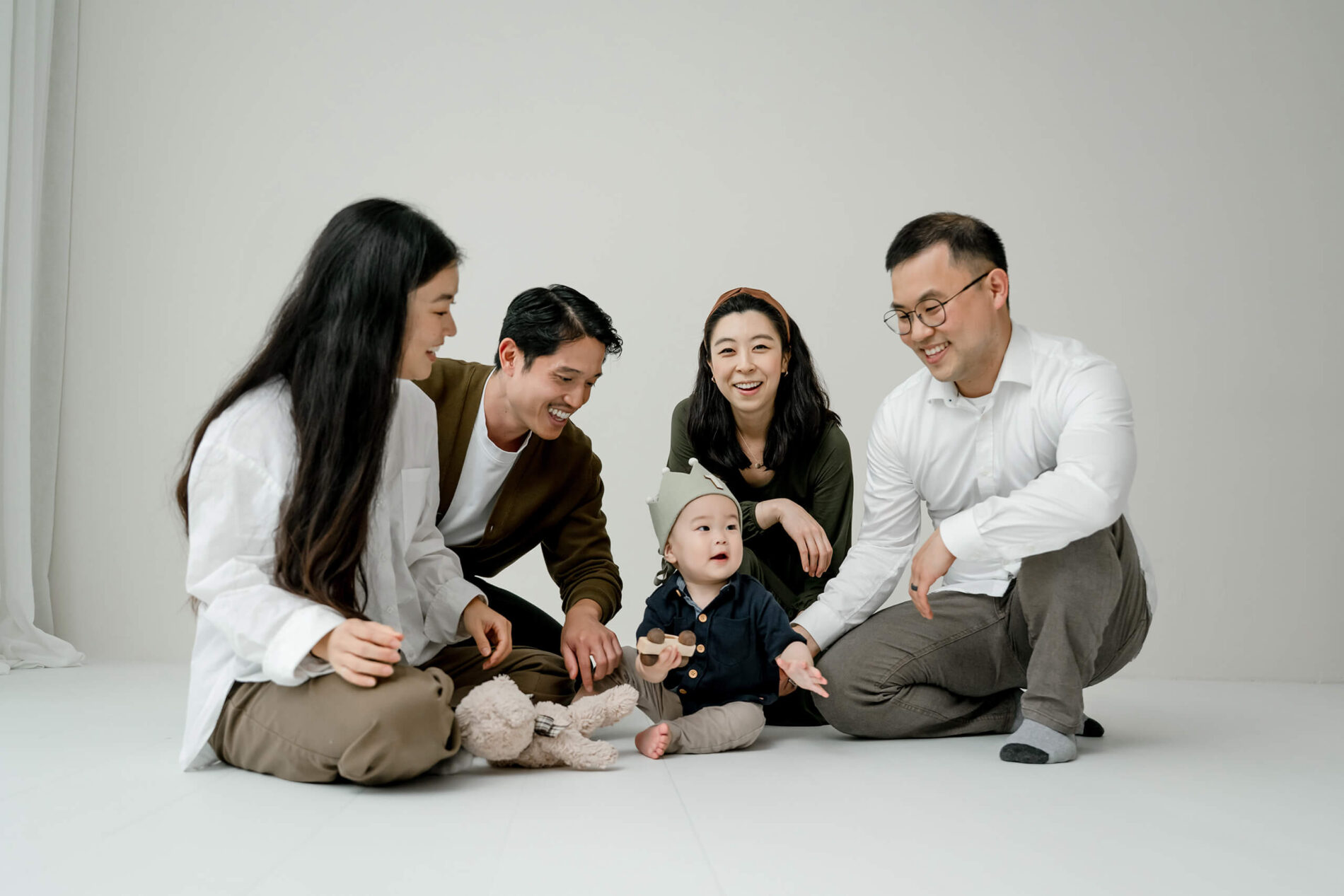 Adults sitting on the studio floor interacting with a baby during a family session near Bellevue.