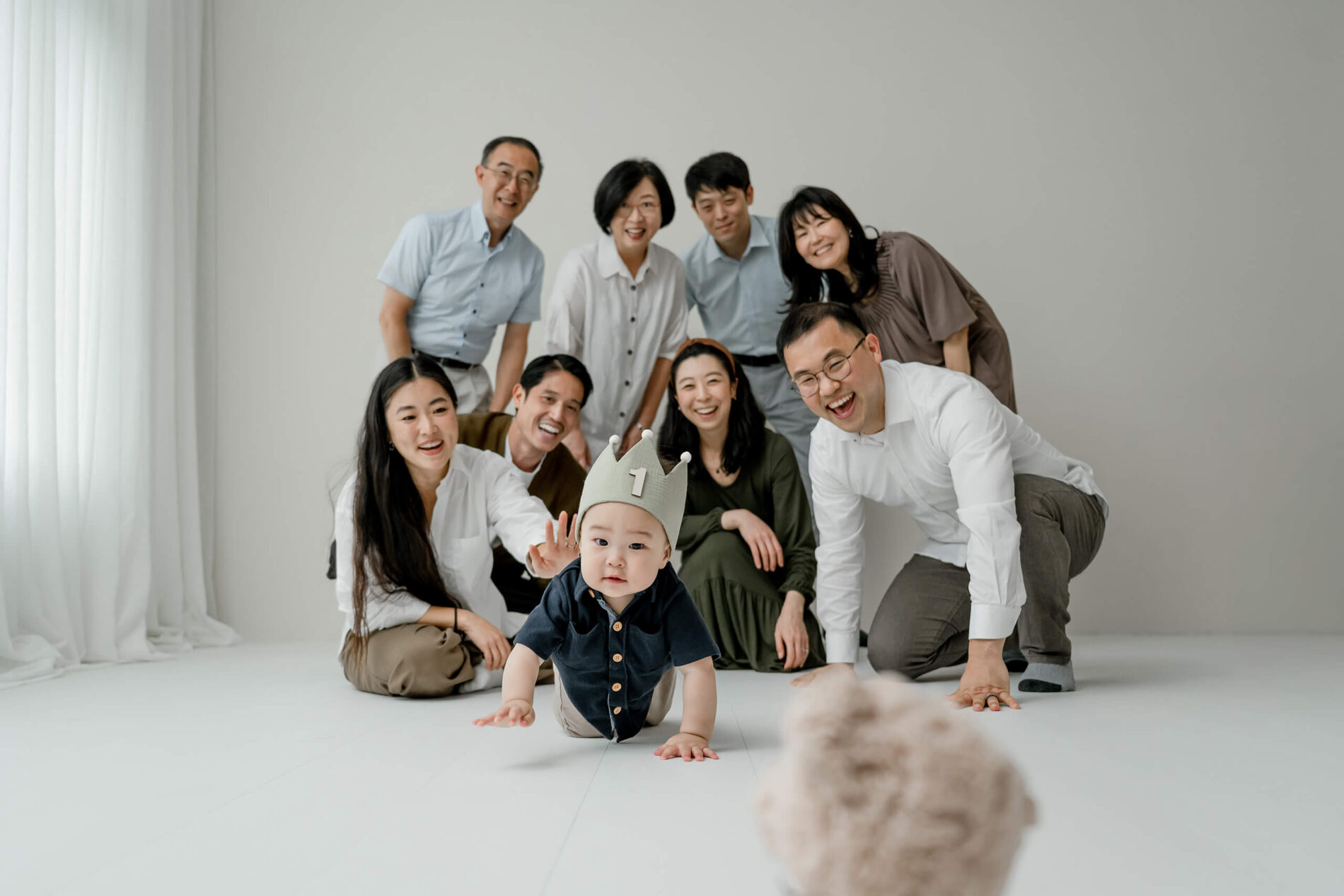 A one-year-old crawling toward the camera with family gathered behind during a Seattle family studio session.