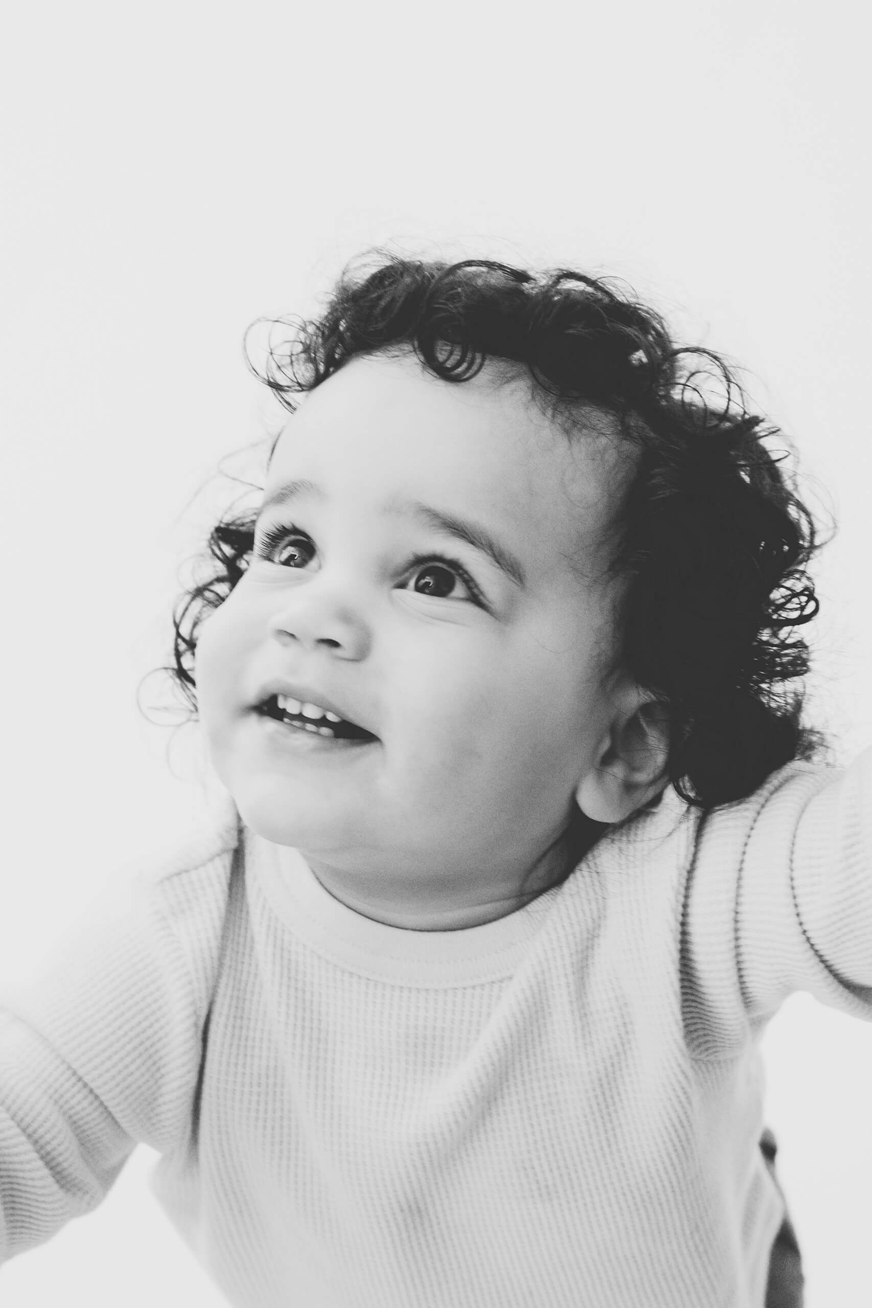 A black-and-white close-up portrait of a toddler smiling during a family studio session near Bellevue.