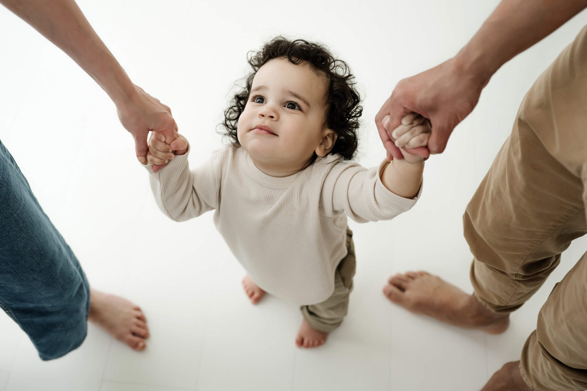 A close-up of a toddler holding both parents’ hands during a family photography session near Bellevue.