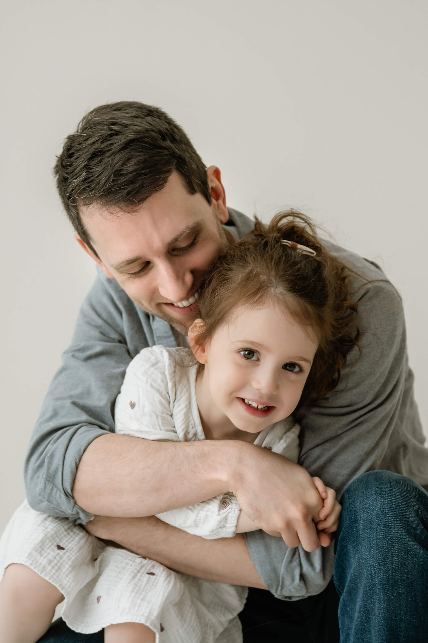A father hugging his smiling daughter during a Kirkland family studio session.