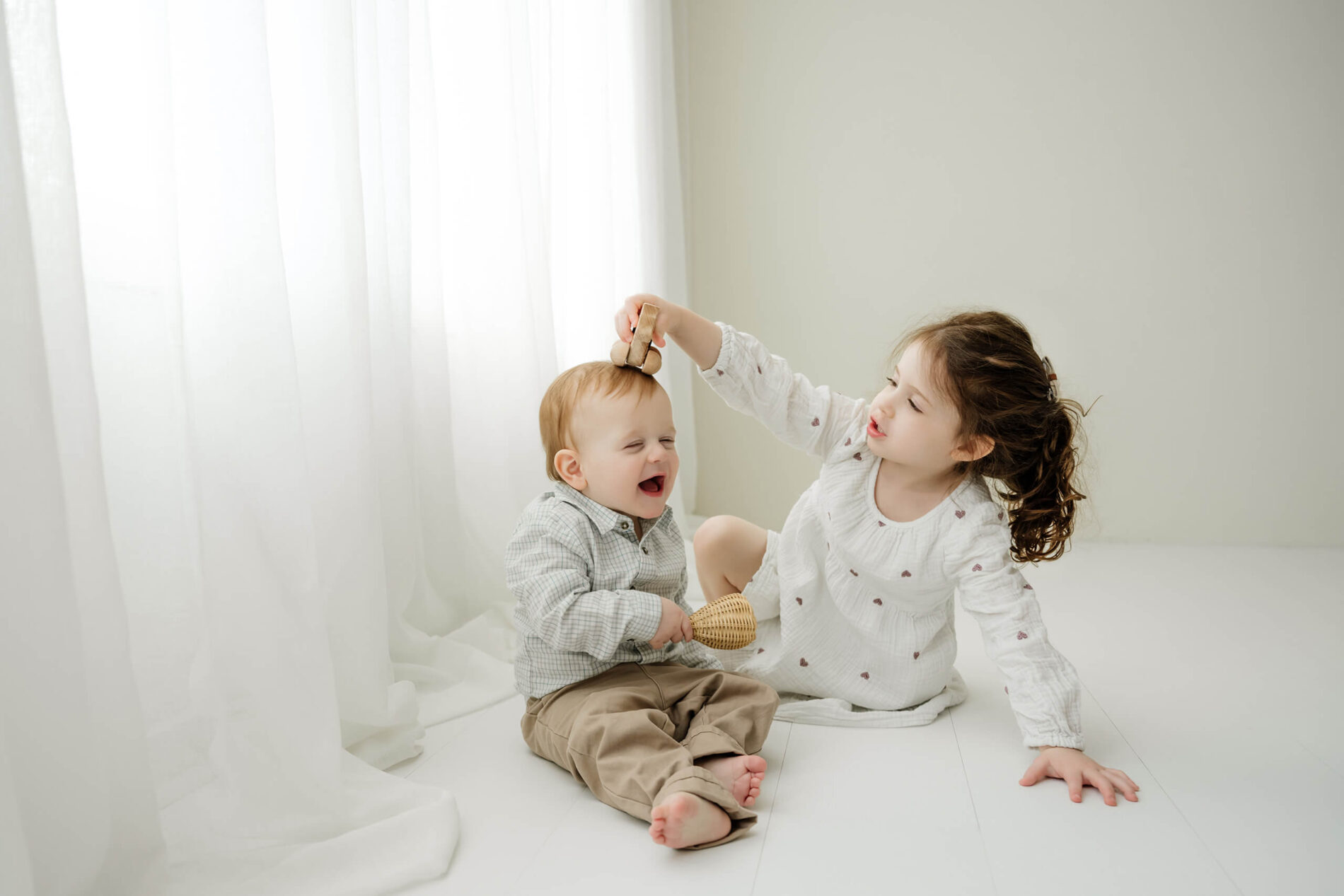 Two siblings playing together on the studio floor during a Seattle family photography session.