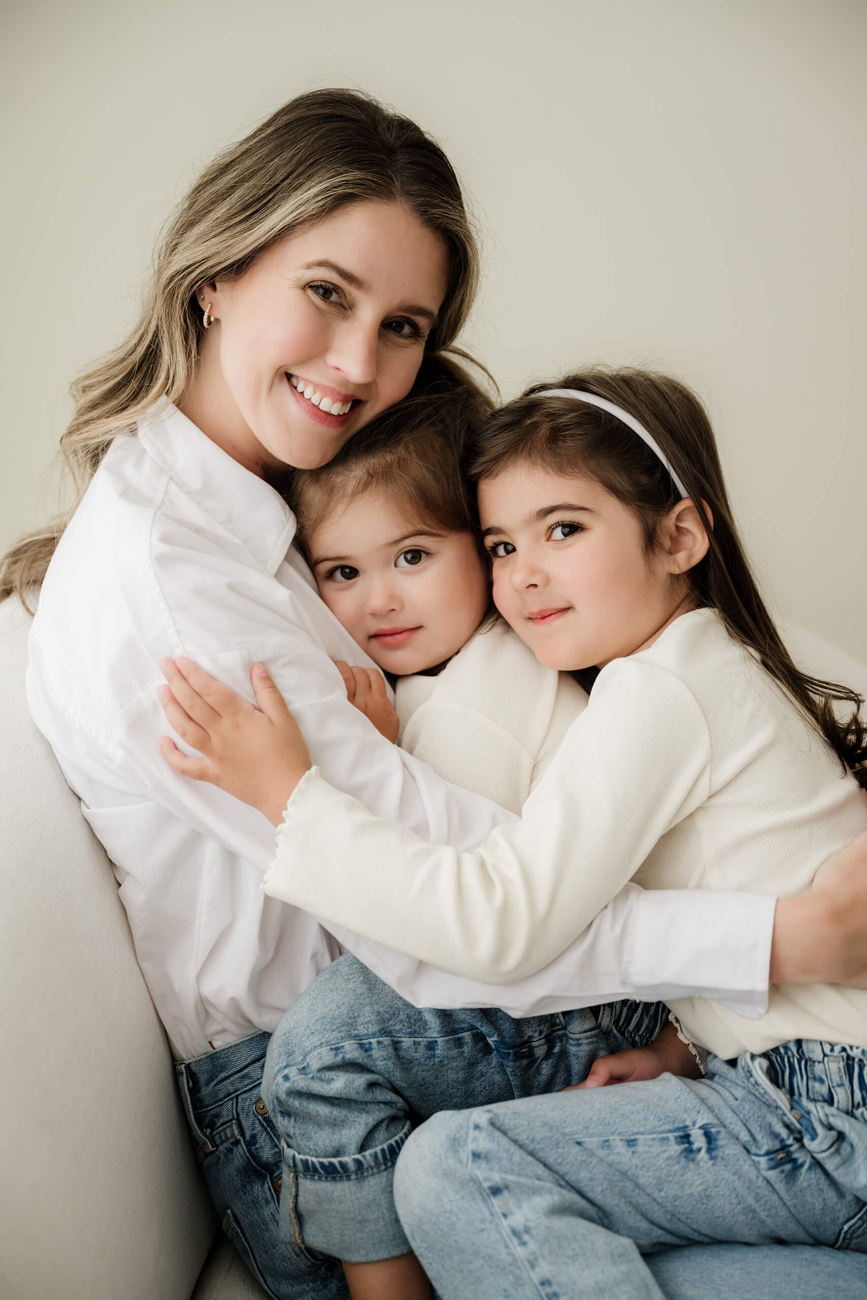 A mother hugs her two young daughters during a relaxed family studio session in Seattle.