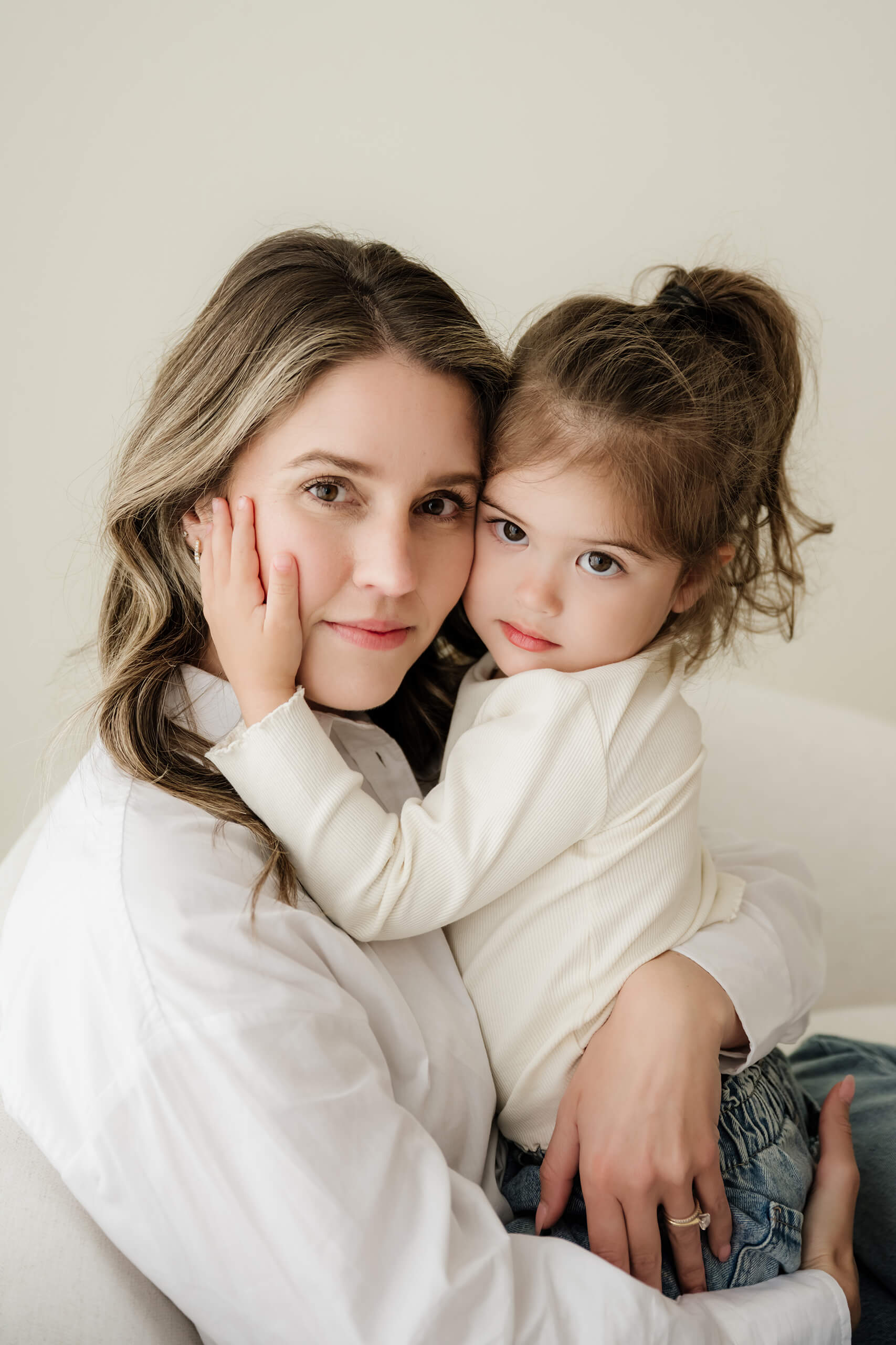 A close-up portrait of a mother holding her toddler daughter in a light-filled Kirkland photography studio.
