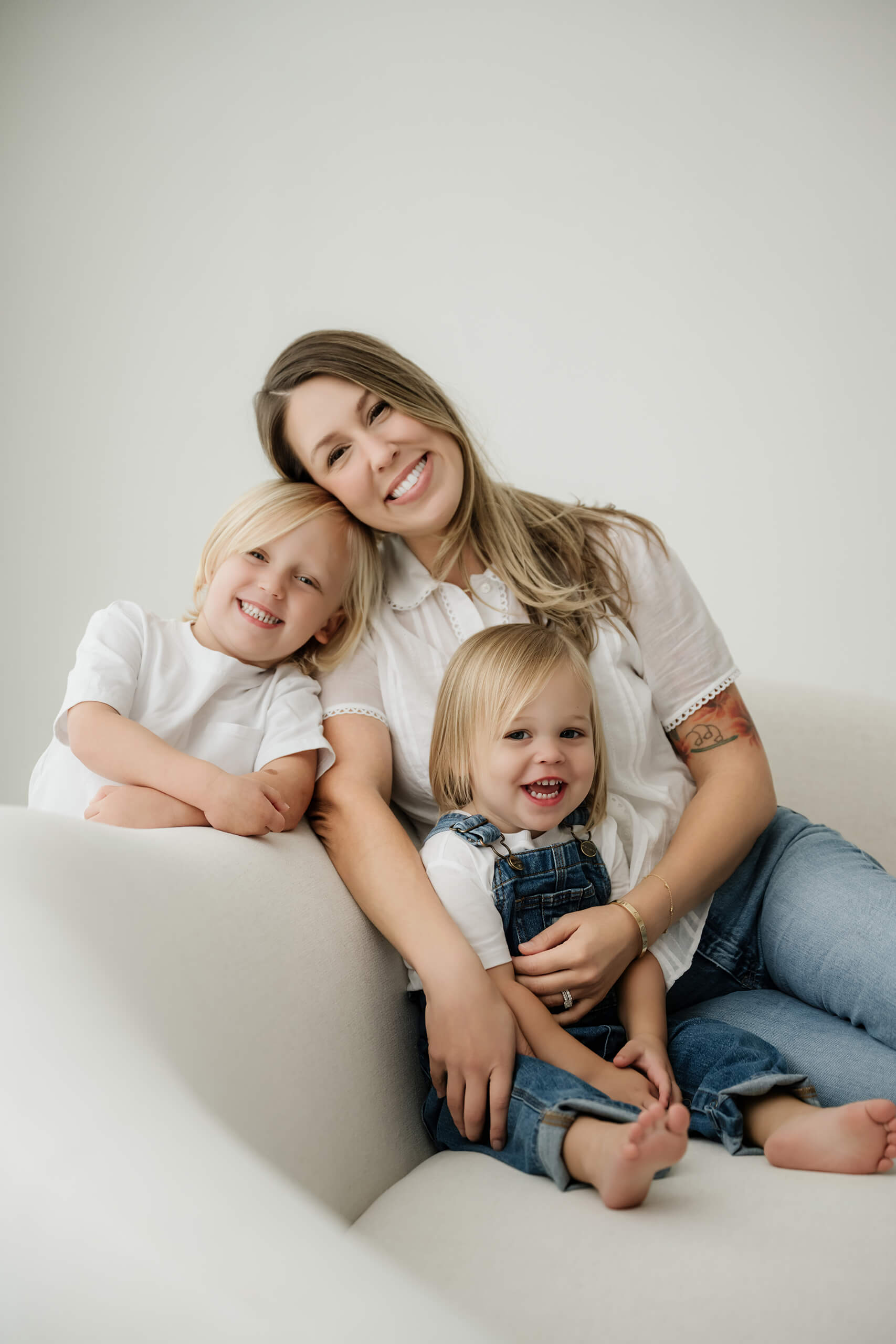 A mother sits with her two young children on a studio couch during a Seattle family session.