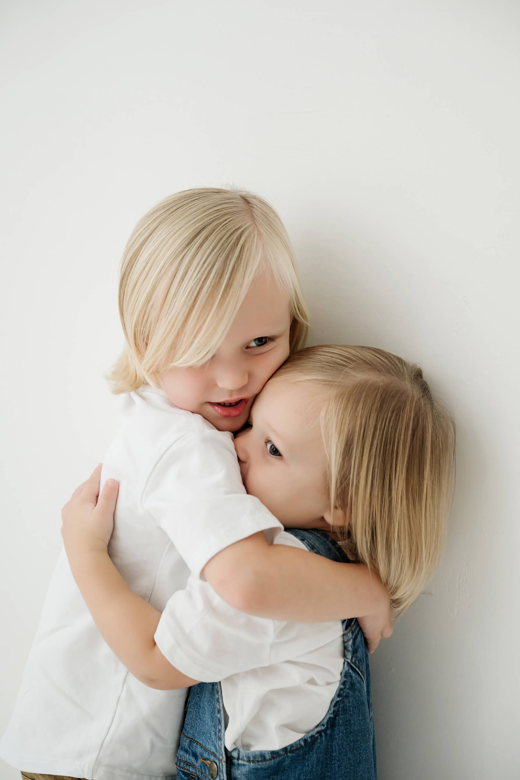 A close sibling portrait captures a gentle hug during a natural family session in Kirkland.