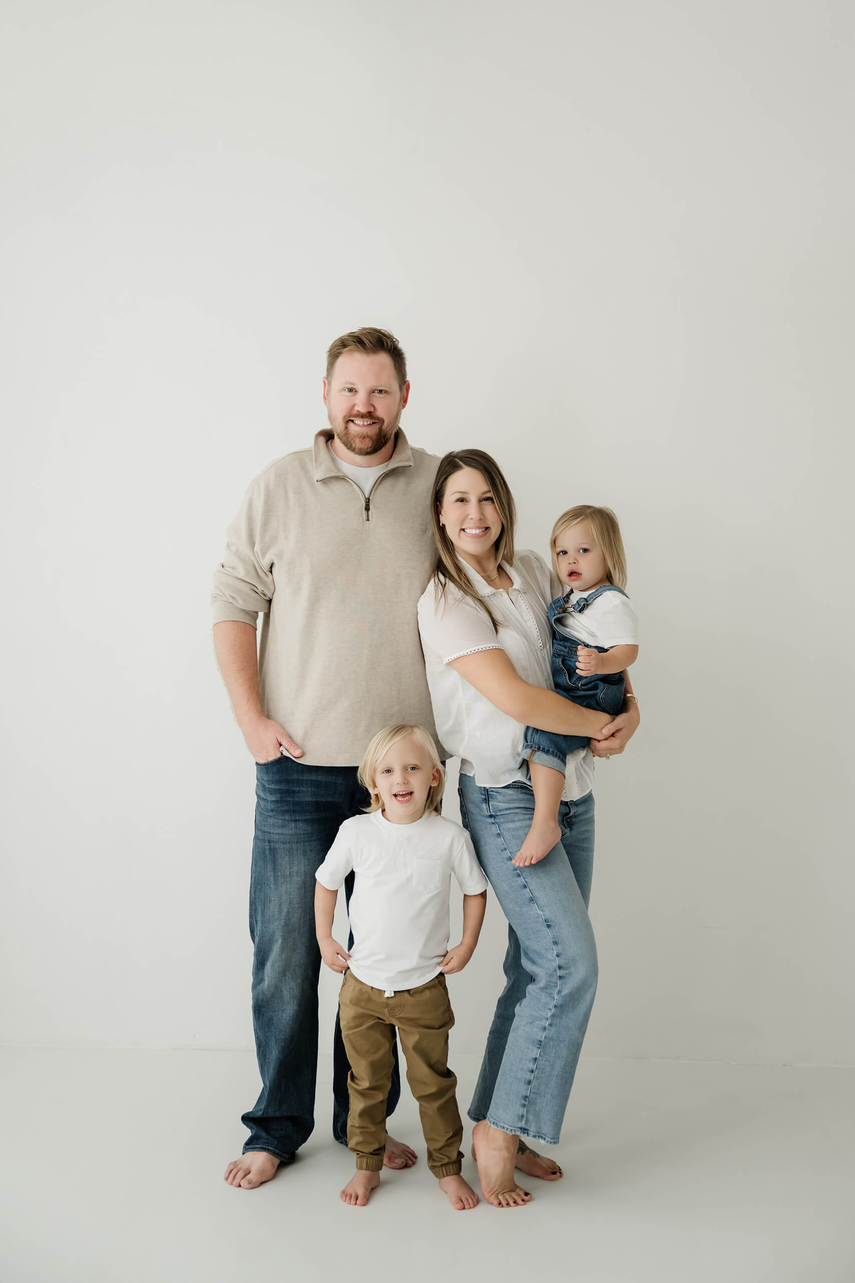 A family of four stands together during a clean, light-filled studio family session in Seattle.