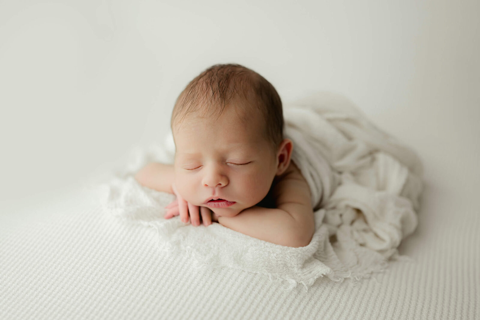 Sleeping 19 day old newborn posed on a white textured blanket during a Seattle newborn studio photoshoot