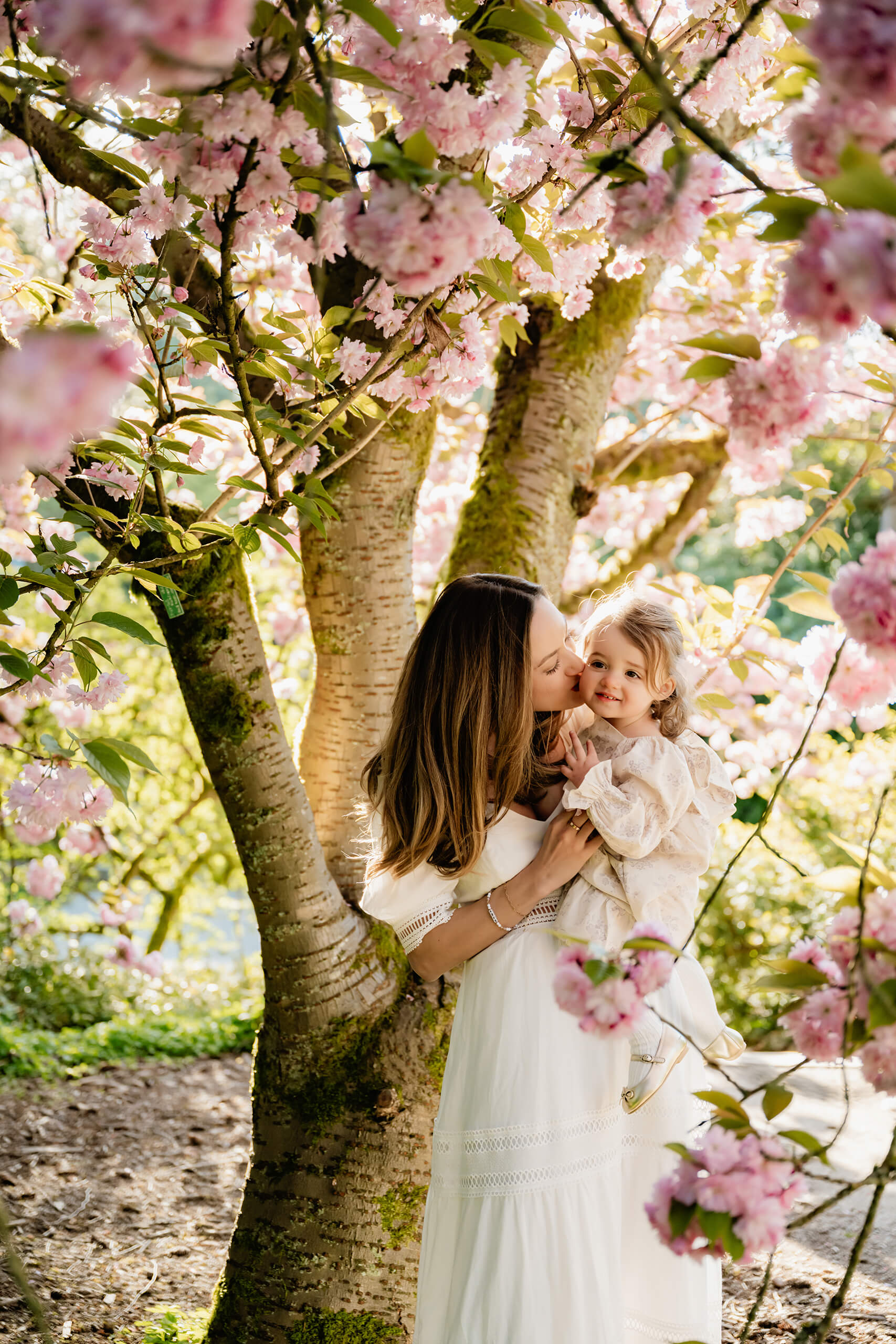 Mother and toddler portrait under blooming cherry blossoms during a Seattle spring family session