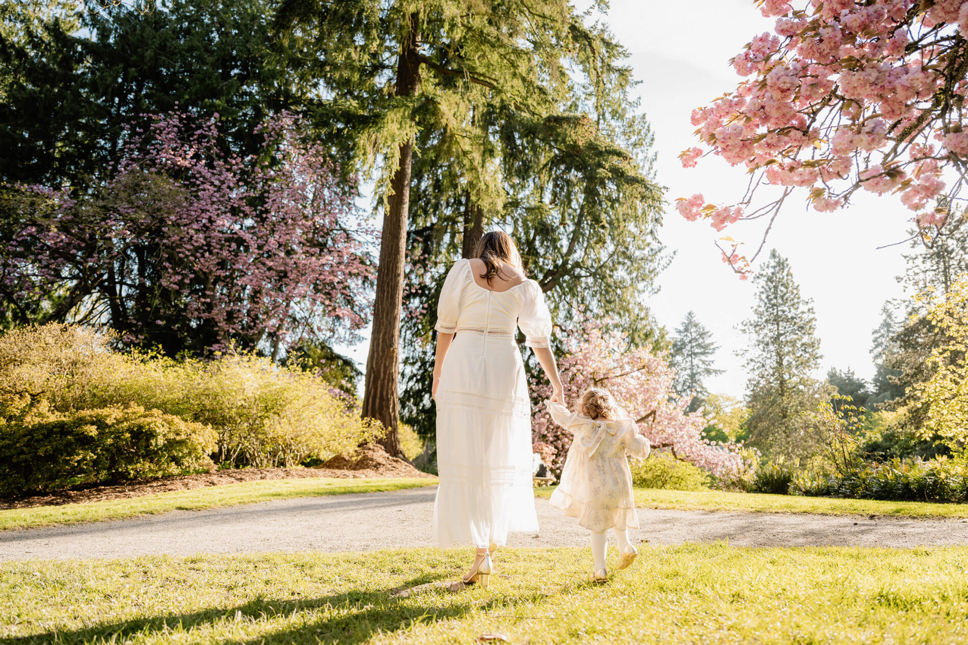 Mother and toddler daughter walking hand in hand through Washington Park Arboretum during a Seattle spring family session