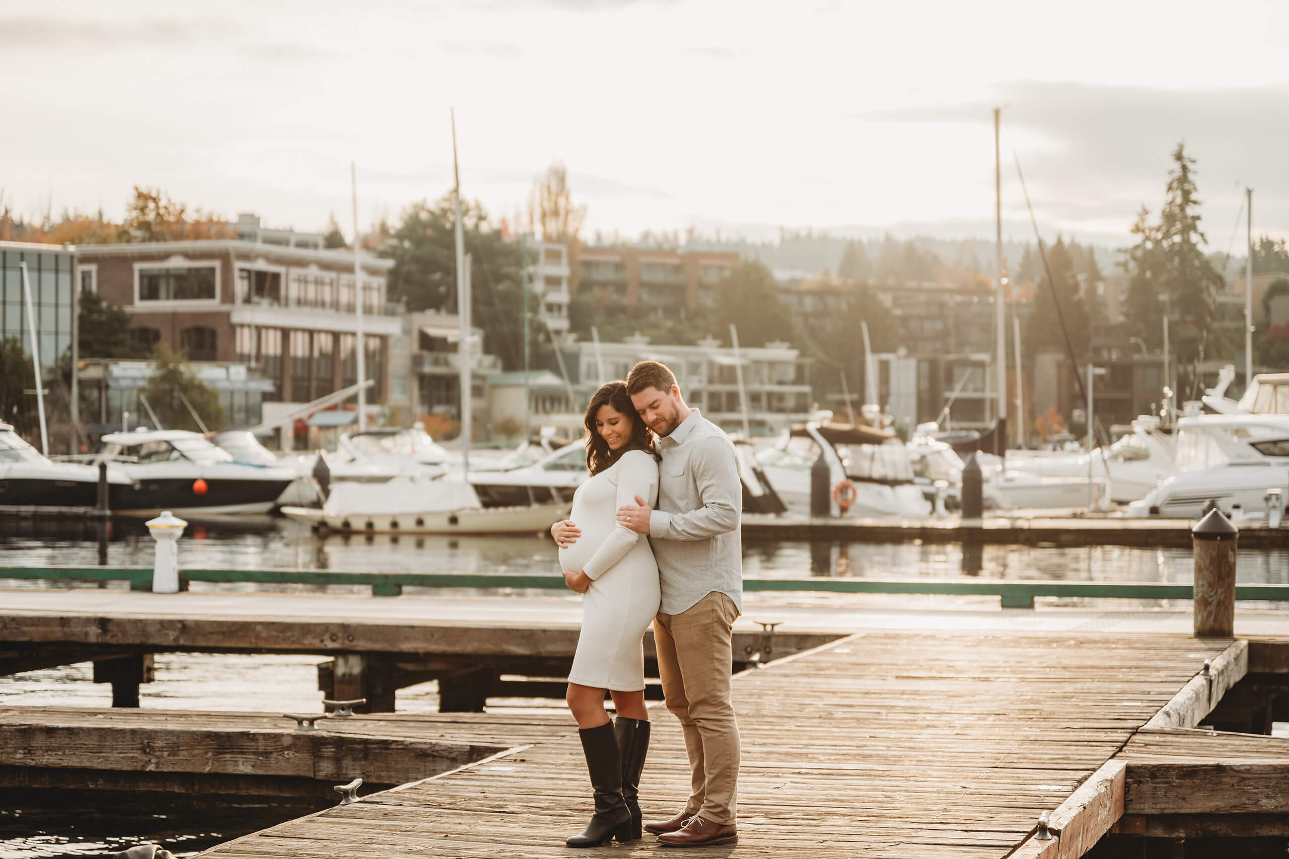 Expecting couple standing on the dock at Kirkland Marina during a soft sunset maternity session.