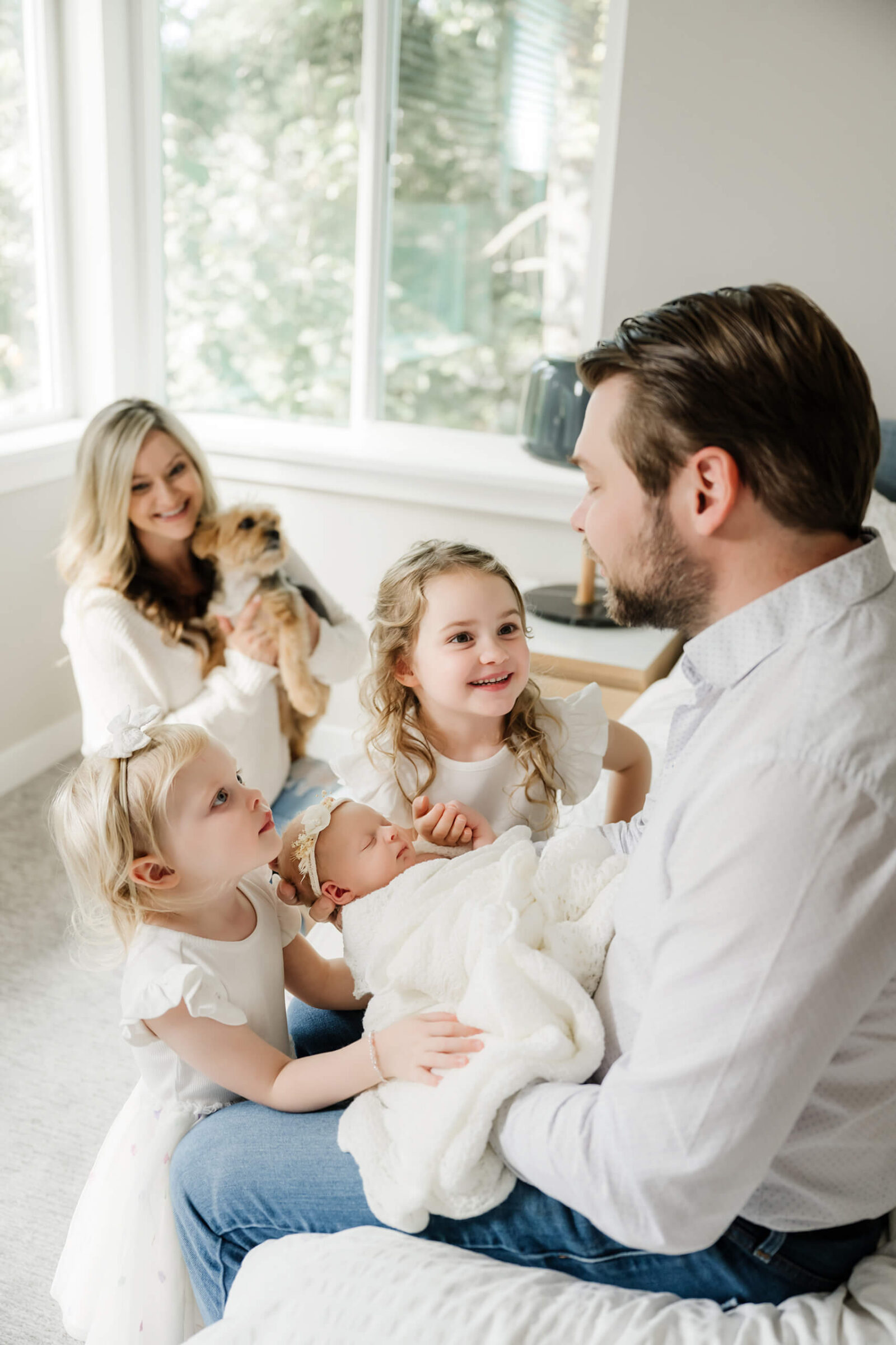 Family gathered around their newborn baby during a relaxed in-home newborn session, part of a maternity and newborn photography package.